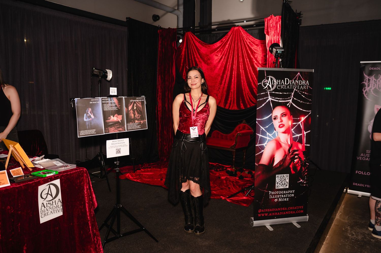 Dark studio space with red fabric backdrops and photography equipment set up for professional portraits.