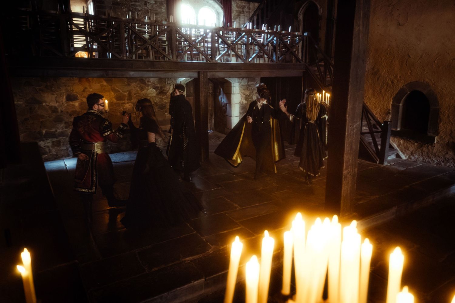 Candlelit medieval chamber scene with figures in period costumes.