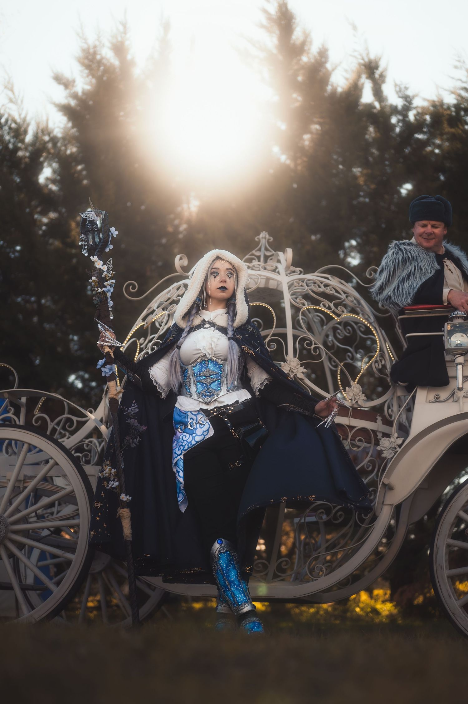 Ornate white carriage with fantasy styling against sunset forest backdrop.