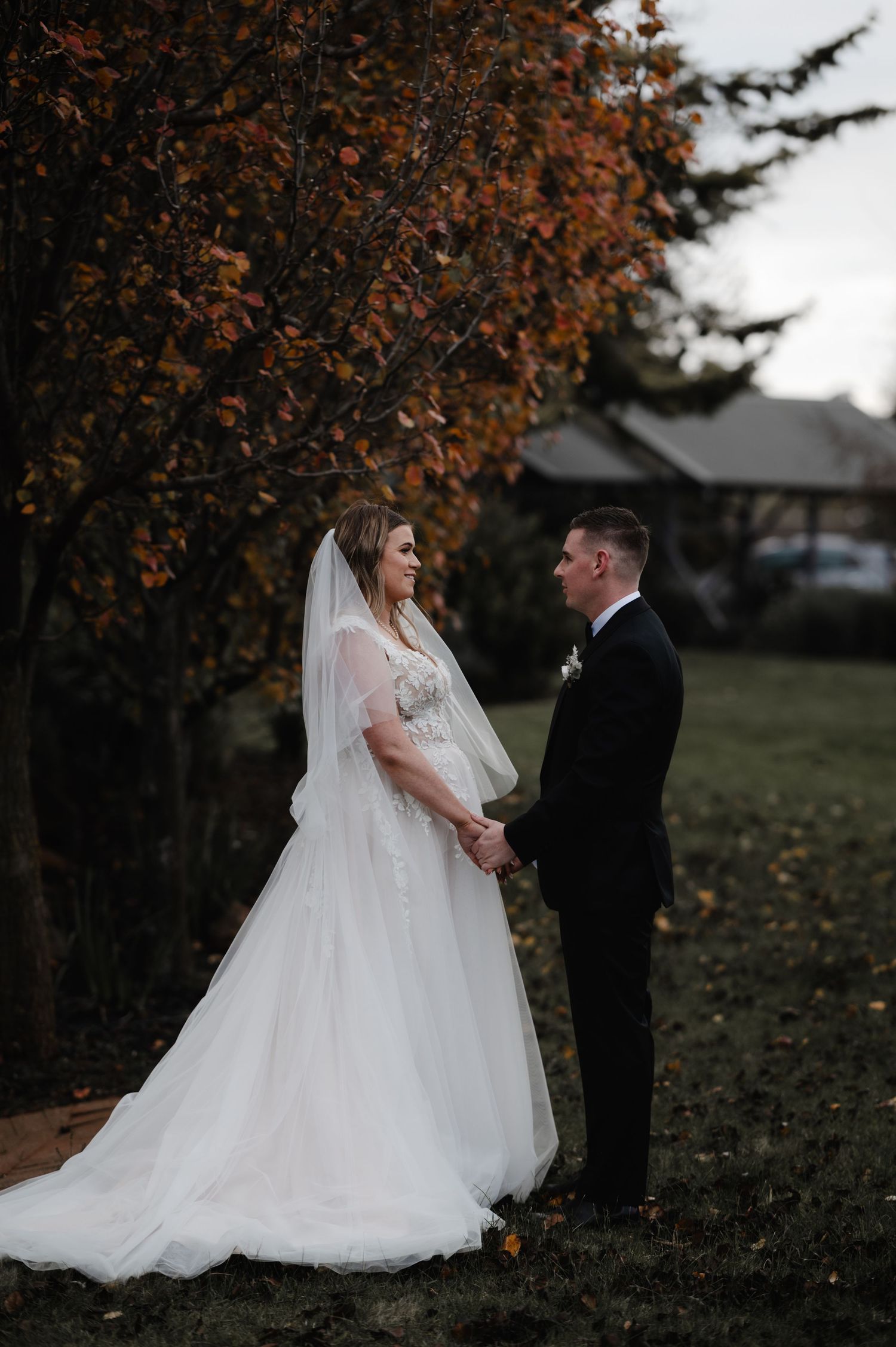 Autumn wedding photoshoot with couple in formal attire among fall foliage.