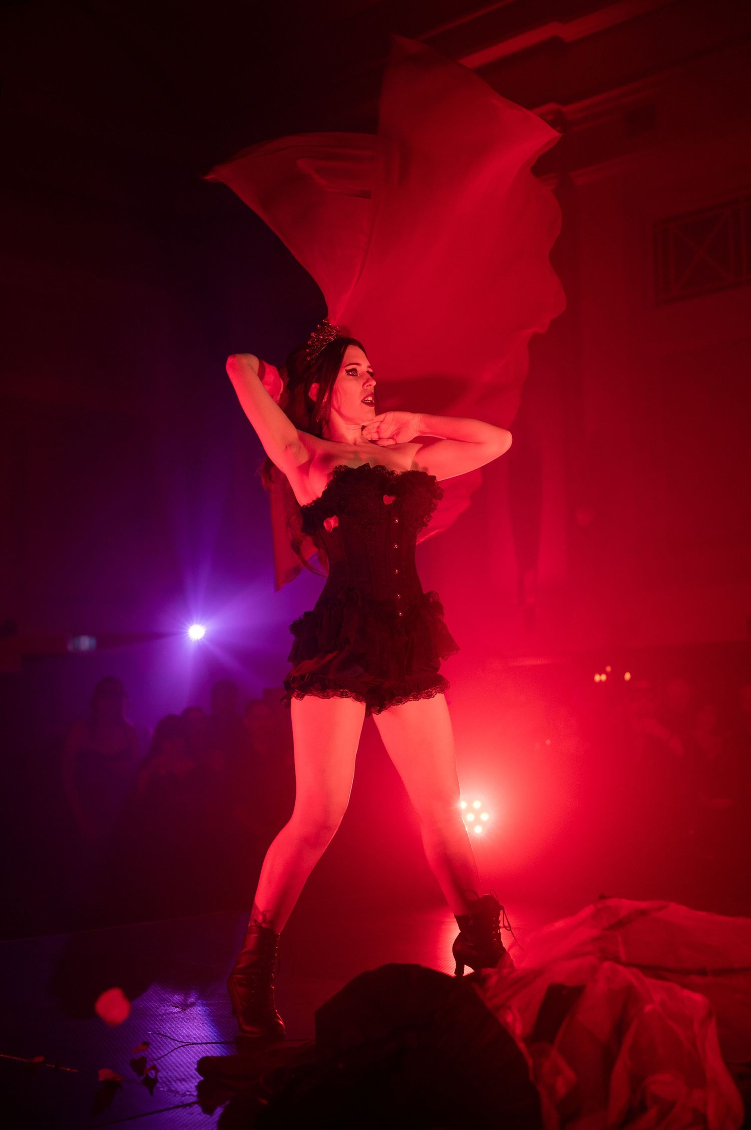 Silhouette of a dancer performing dynamic moves against dramatic red and purple stage lighting.