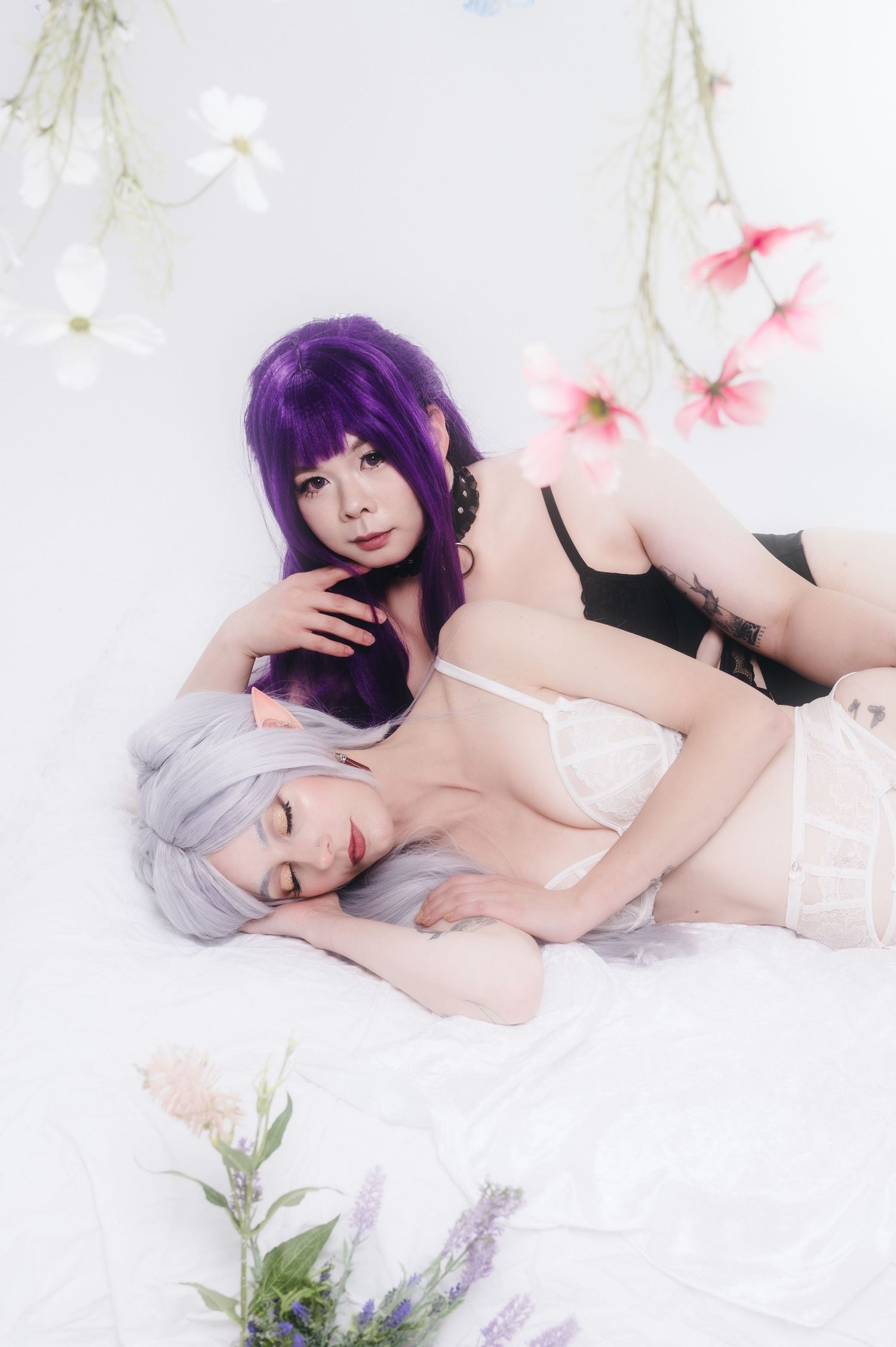 Artistic boudoir photoshoot featuring soft lighting, pink cherry blossoms, and delicate white bedding.