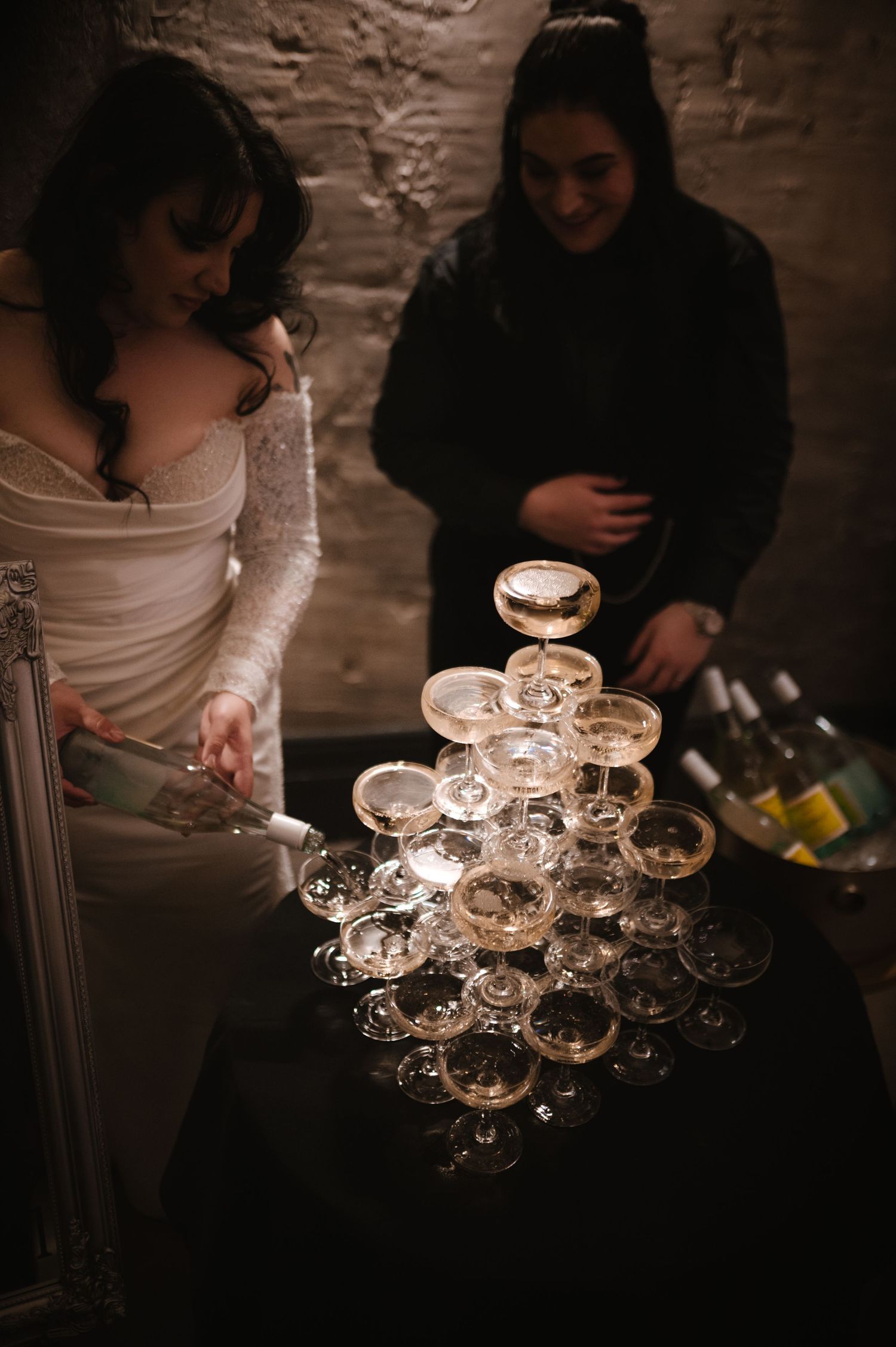 Vintage champagne coupes arranged in a pyramid formation at a wedding reception.