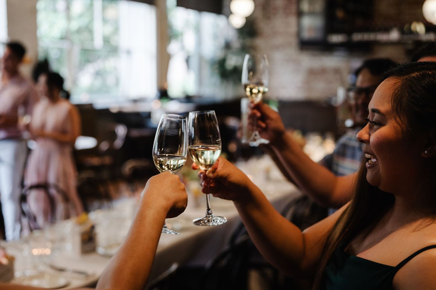 Wedding guests raising glasses in a toast during reception celebration.