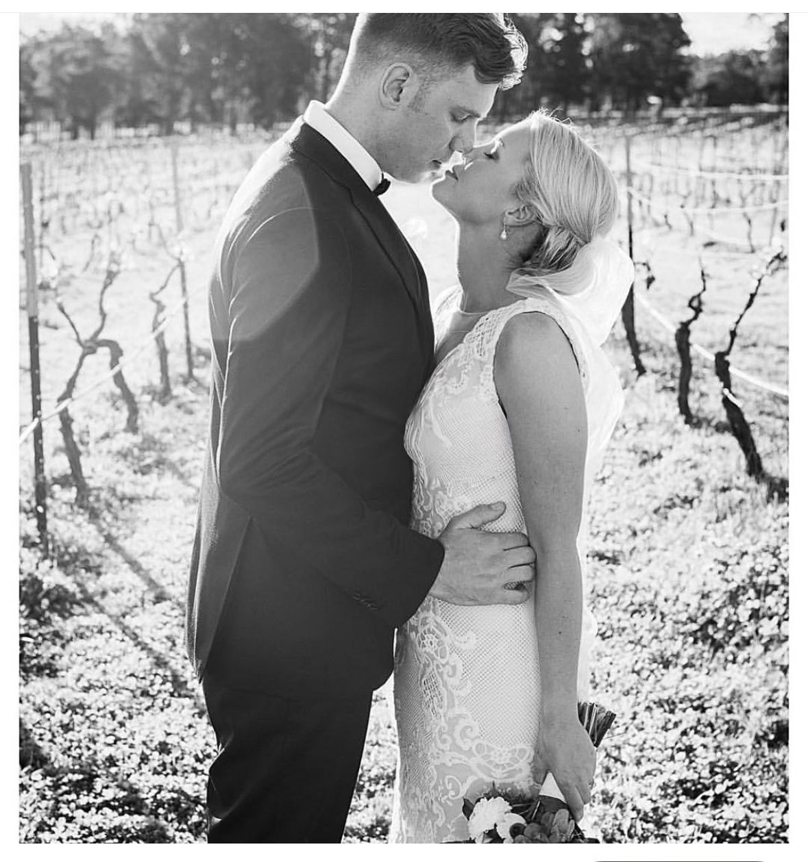 A romantic black and white photo series of a couple embracing in a snowy vineyard during winter.