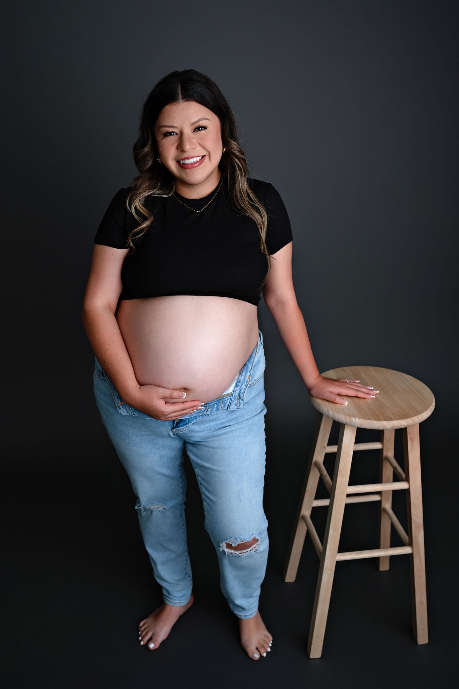 Four progressive images showing someone in ripped jeans posing next to a wooden stool against a dark background.