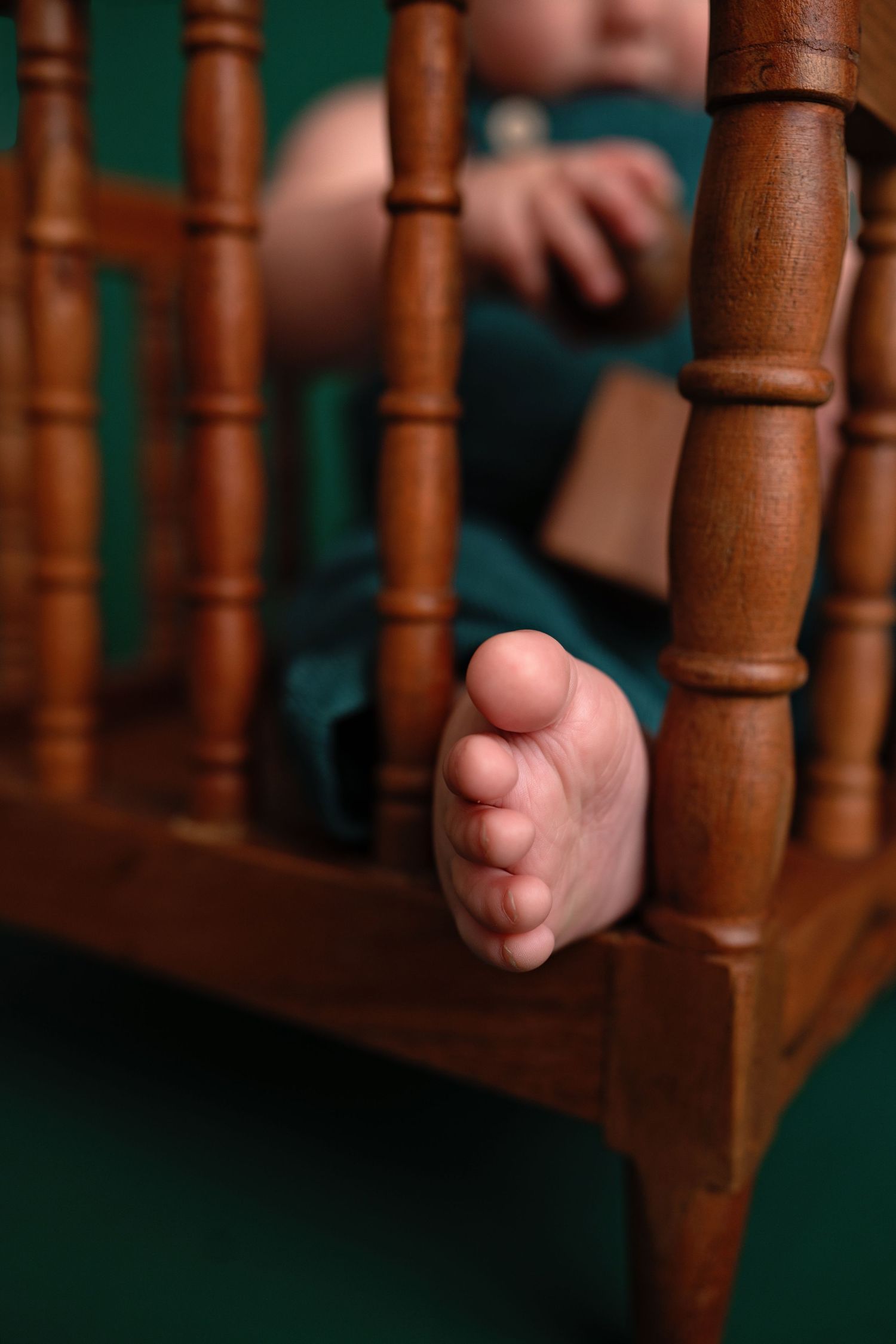 Small baby feet gripping wooden spindles of a staircase or banister railing.