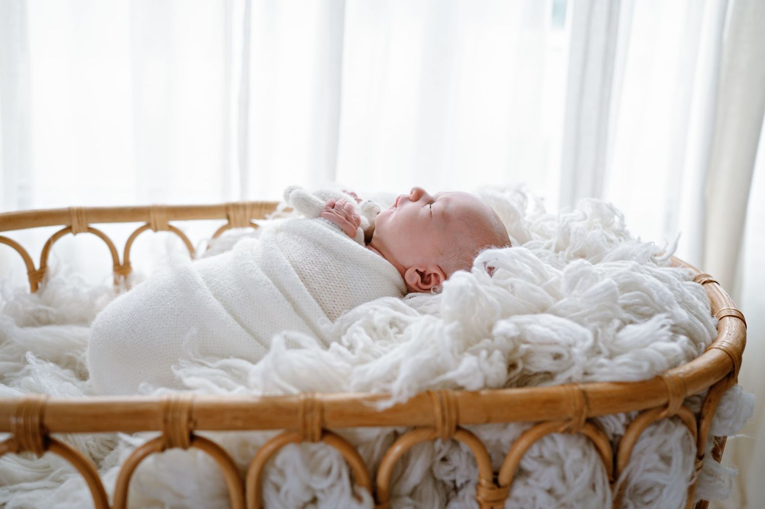 Cozy family scene with white bedding and natural light streaming through windows.