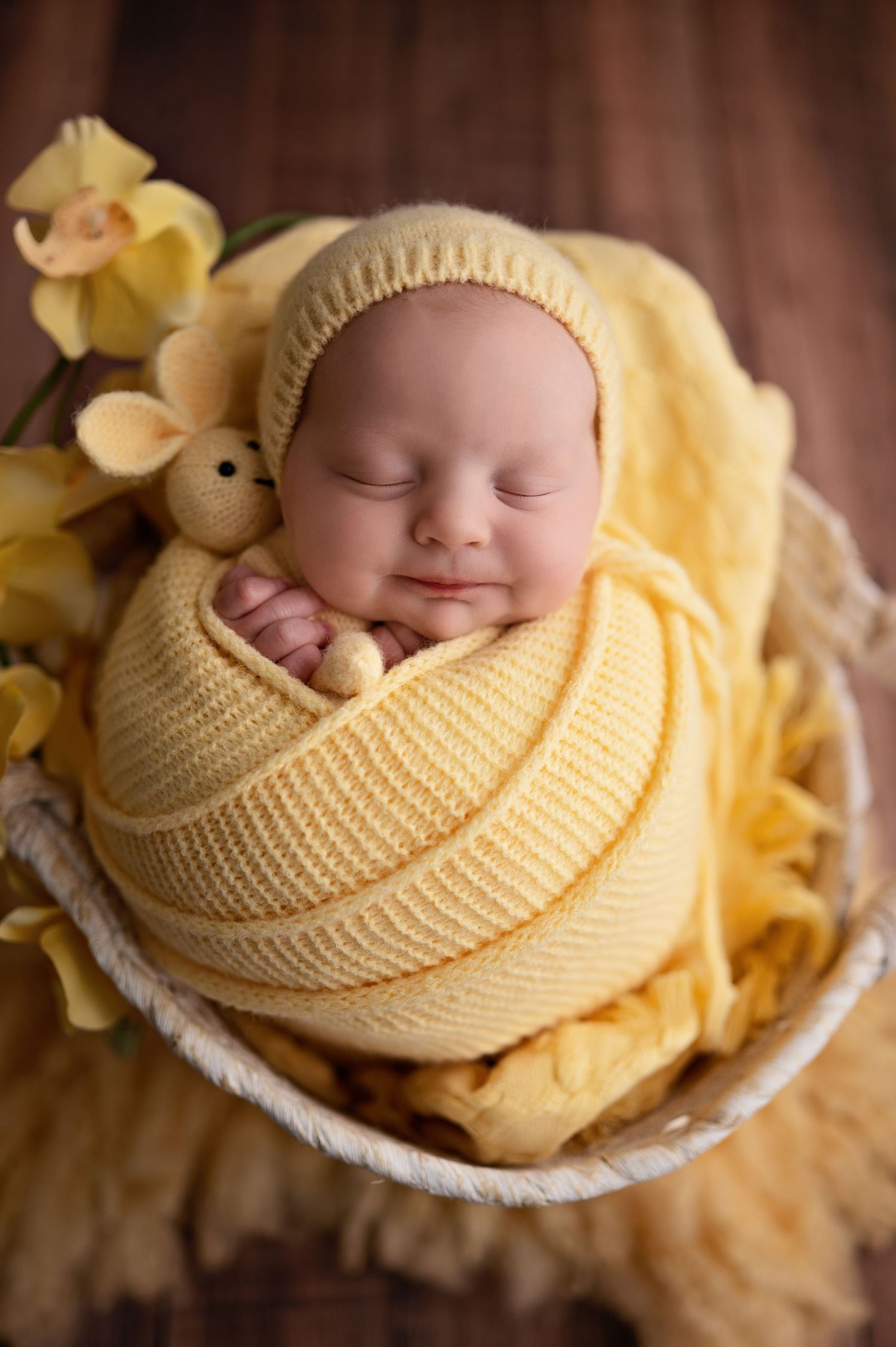 A sleeping baby swaddled in soft yellow knitted blankets with delicate floral accents in a series of peaceful poses.