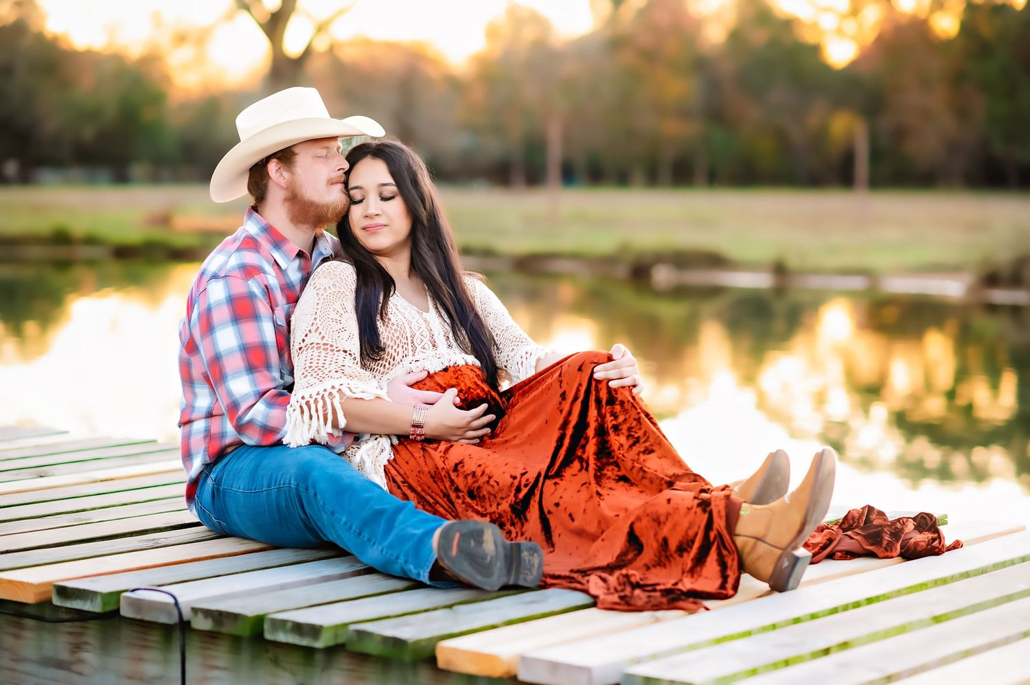 Romantic couple photo on dock at sunset with velvet dress and western attire.