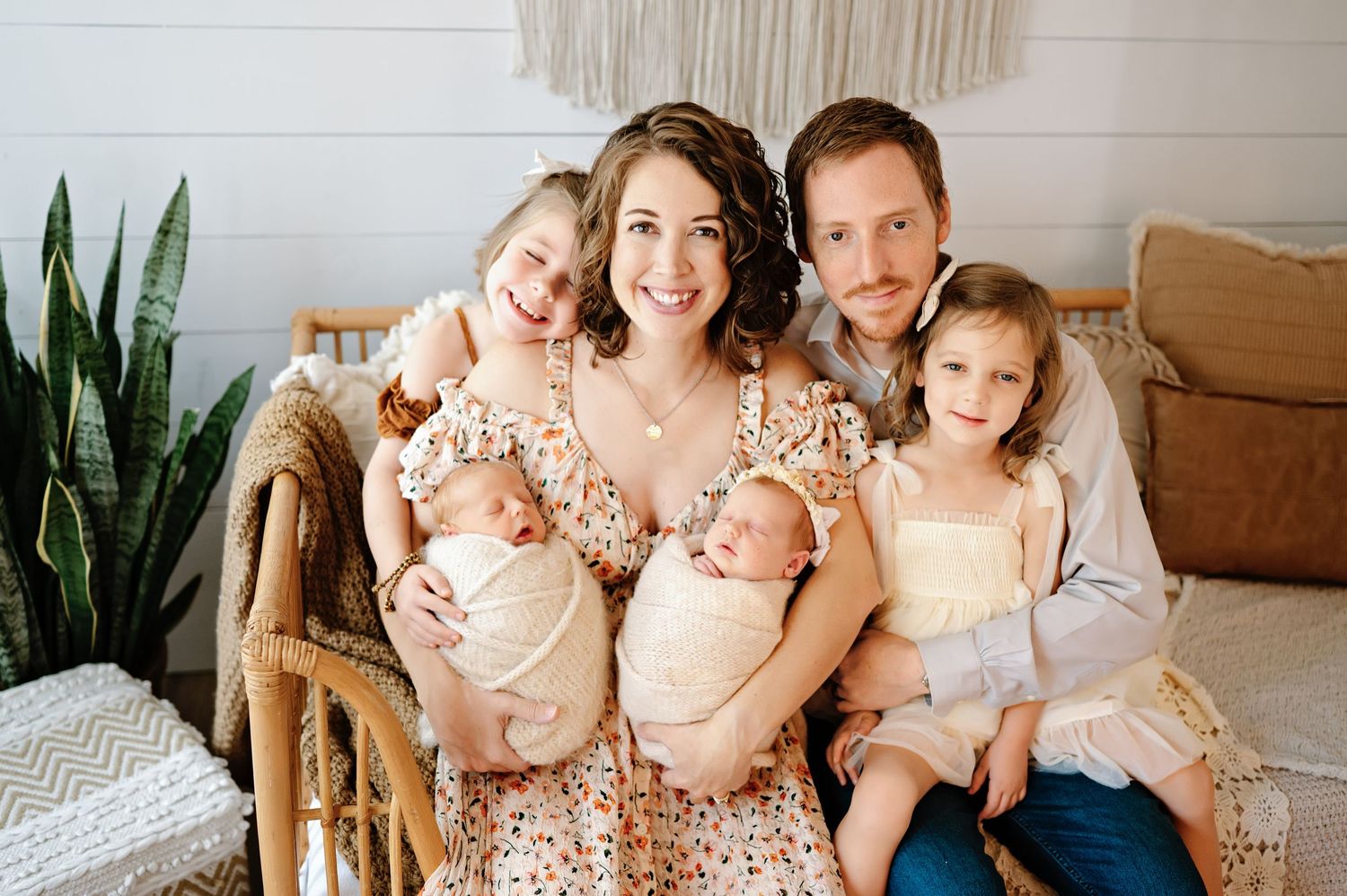 Happy family of five posing for a professional newborn photo session with twin babies and two young daughters.