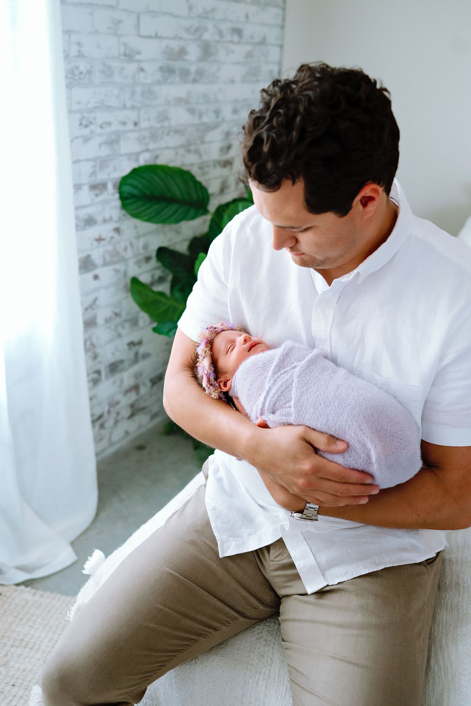 Tender moment between parent and newborn in bright modern setting.
