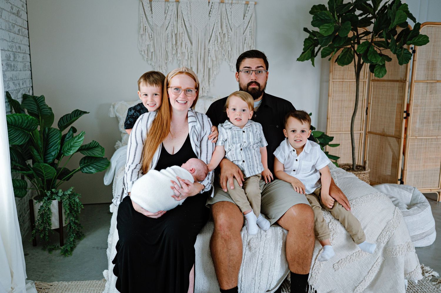 Family portrait session in bright room with white decor and indoor plants.