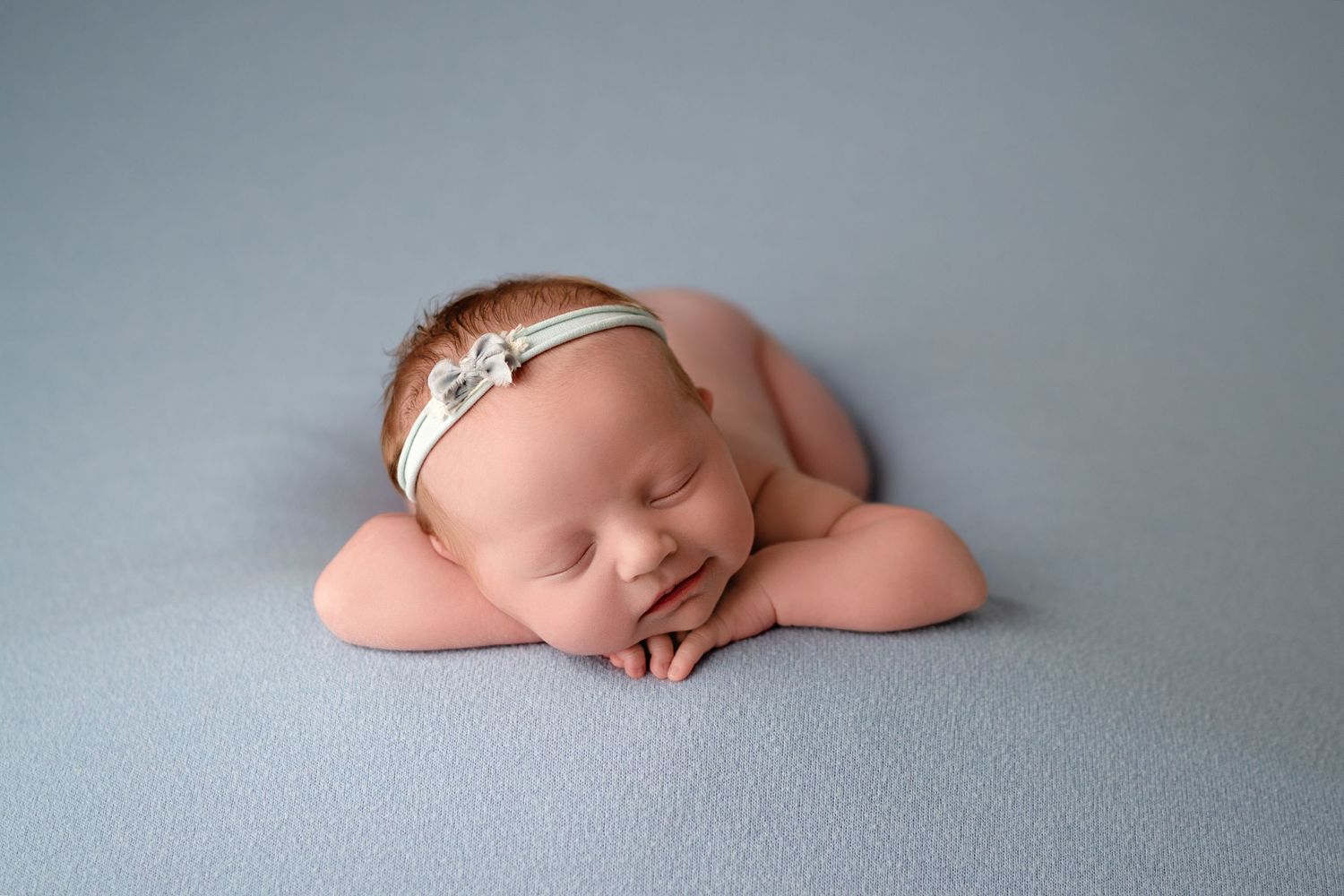 Artistic black and white newborn photography series showing peaceful sleeping baby in minimalist poses on soft backdrop.