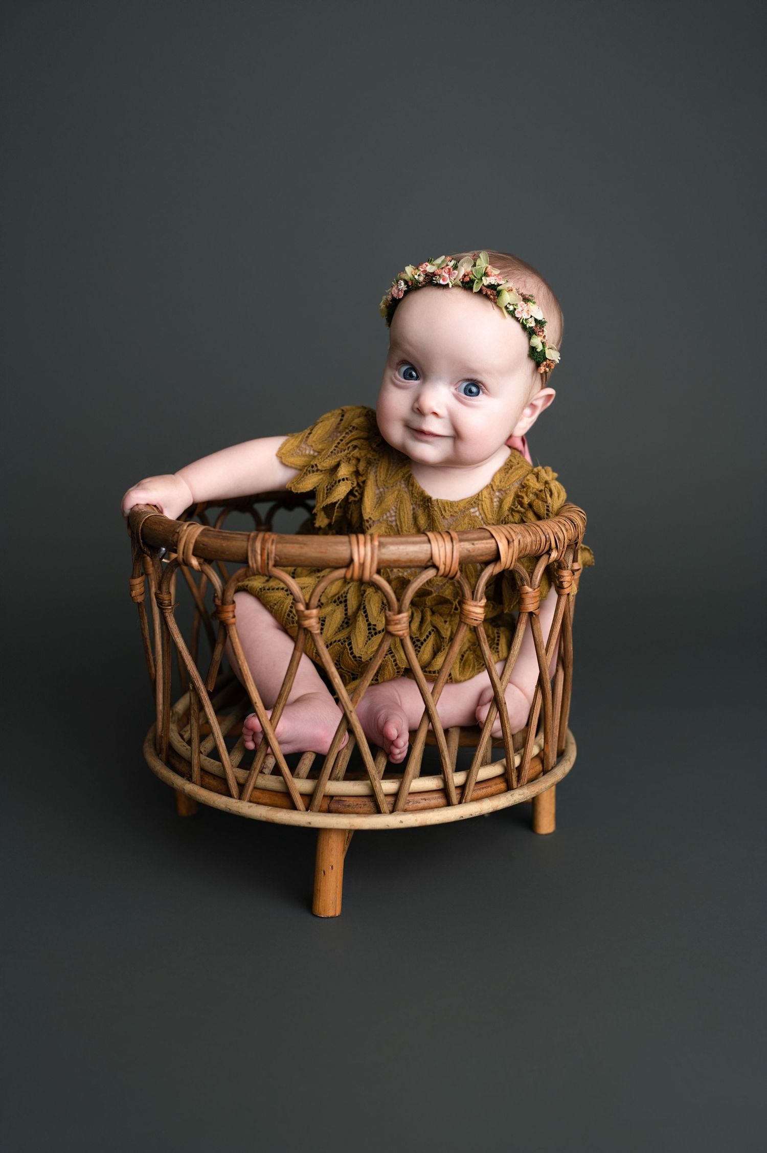 Studio portrait of a wooden basket prop against dark background with decorative floral crown accent.