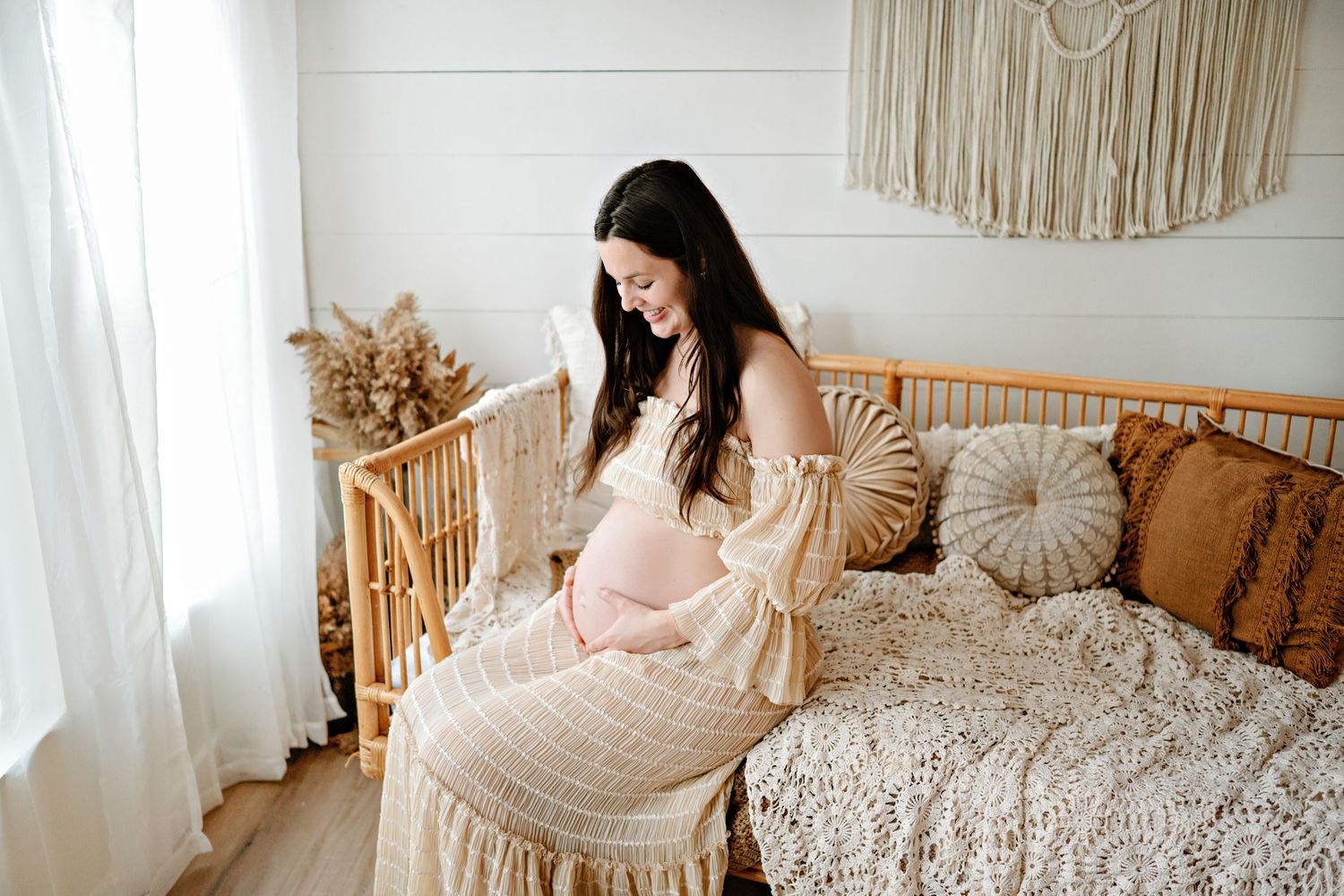 A cozy boho bedroom features a macrame wall hanging, rattan chair, and plush bedding in neutral tones.