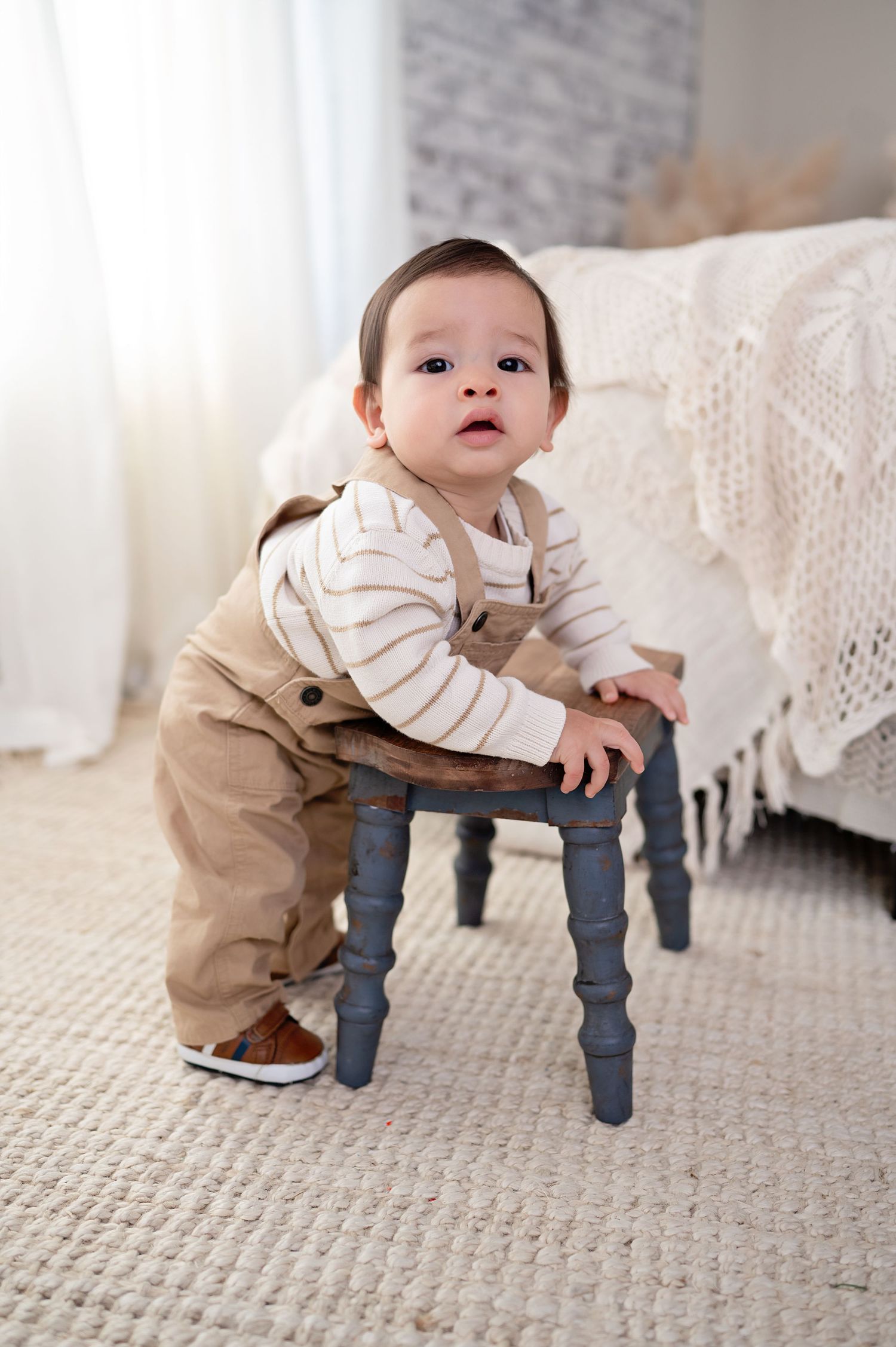A sequence of milestone photos showing a baby learning to pull up and cruise along furniture on a beige carpet.
