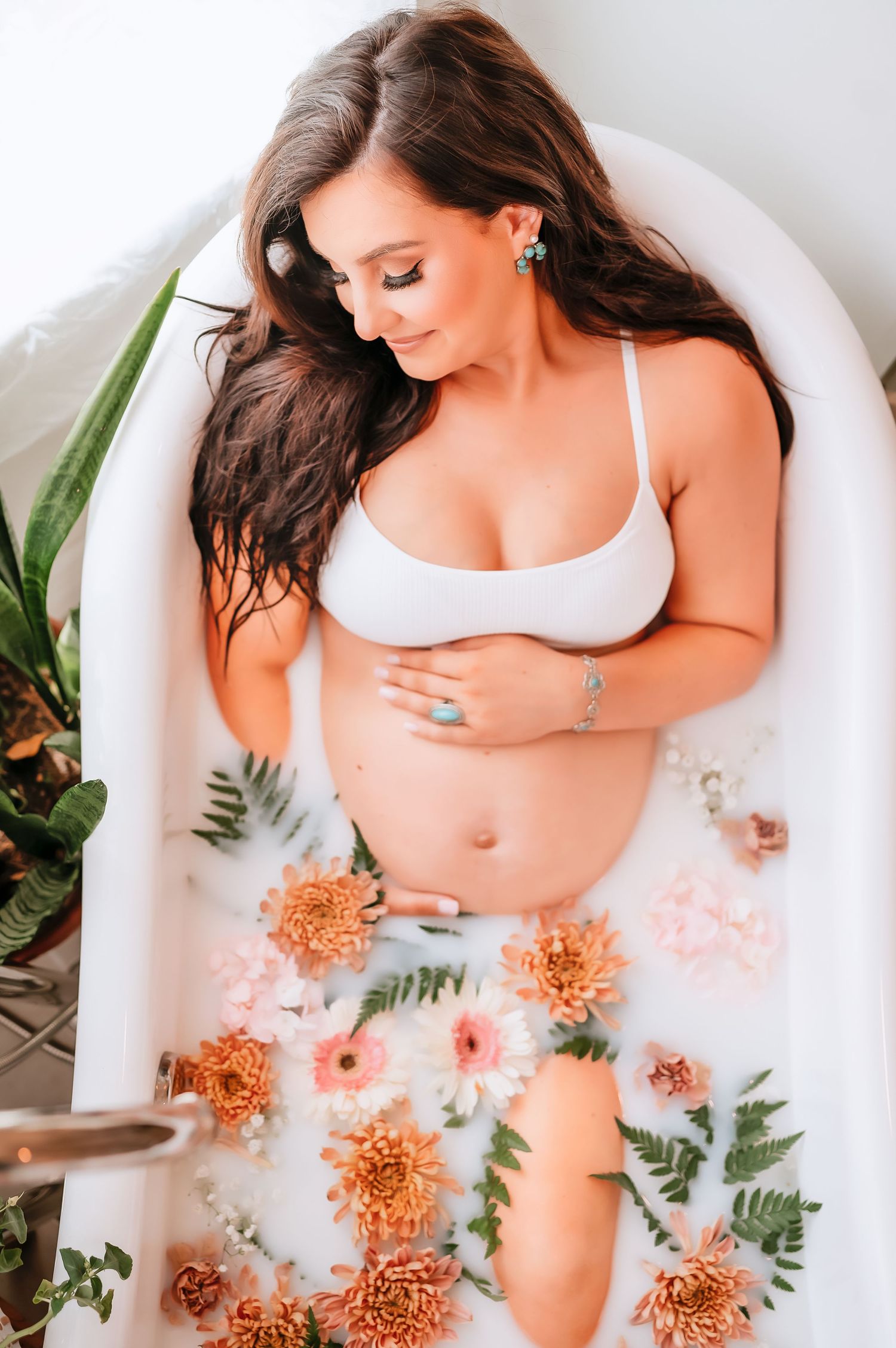 A milk bath photoshoot featuring peach flowers and greenery creates a dreamy and romantic aesthetic.