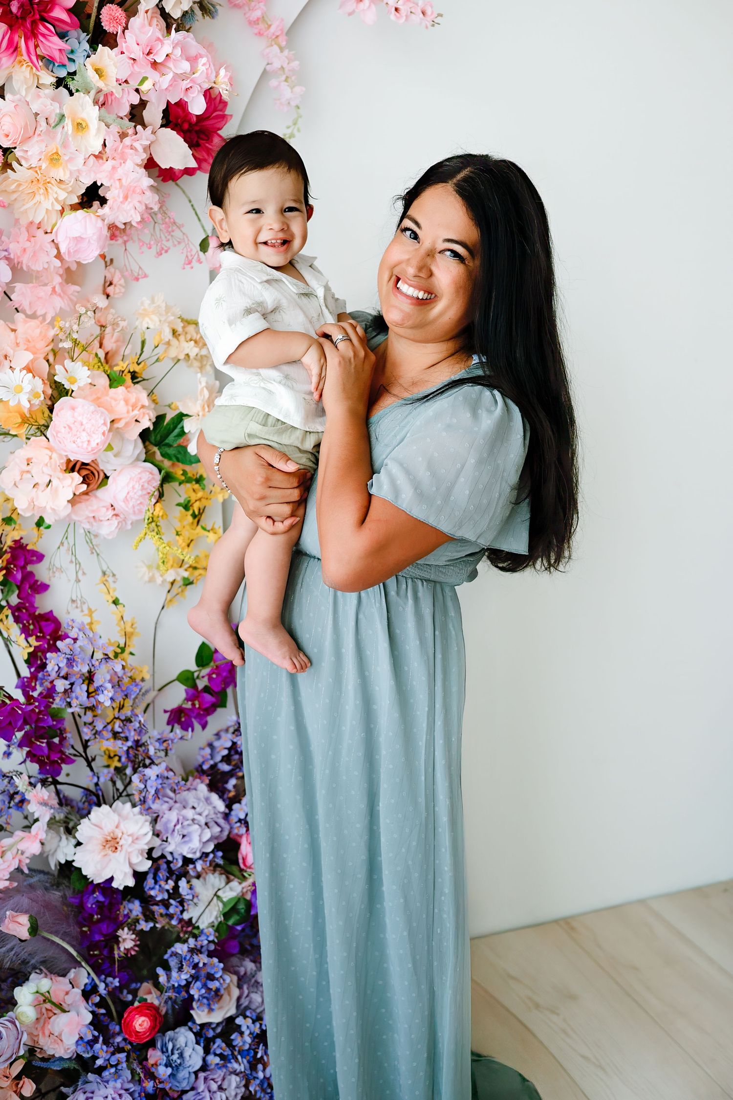 Floral photo backdrop with pink and purple flowers against a white wall.