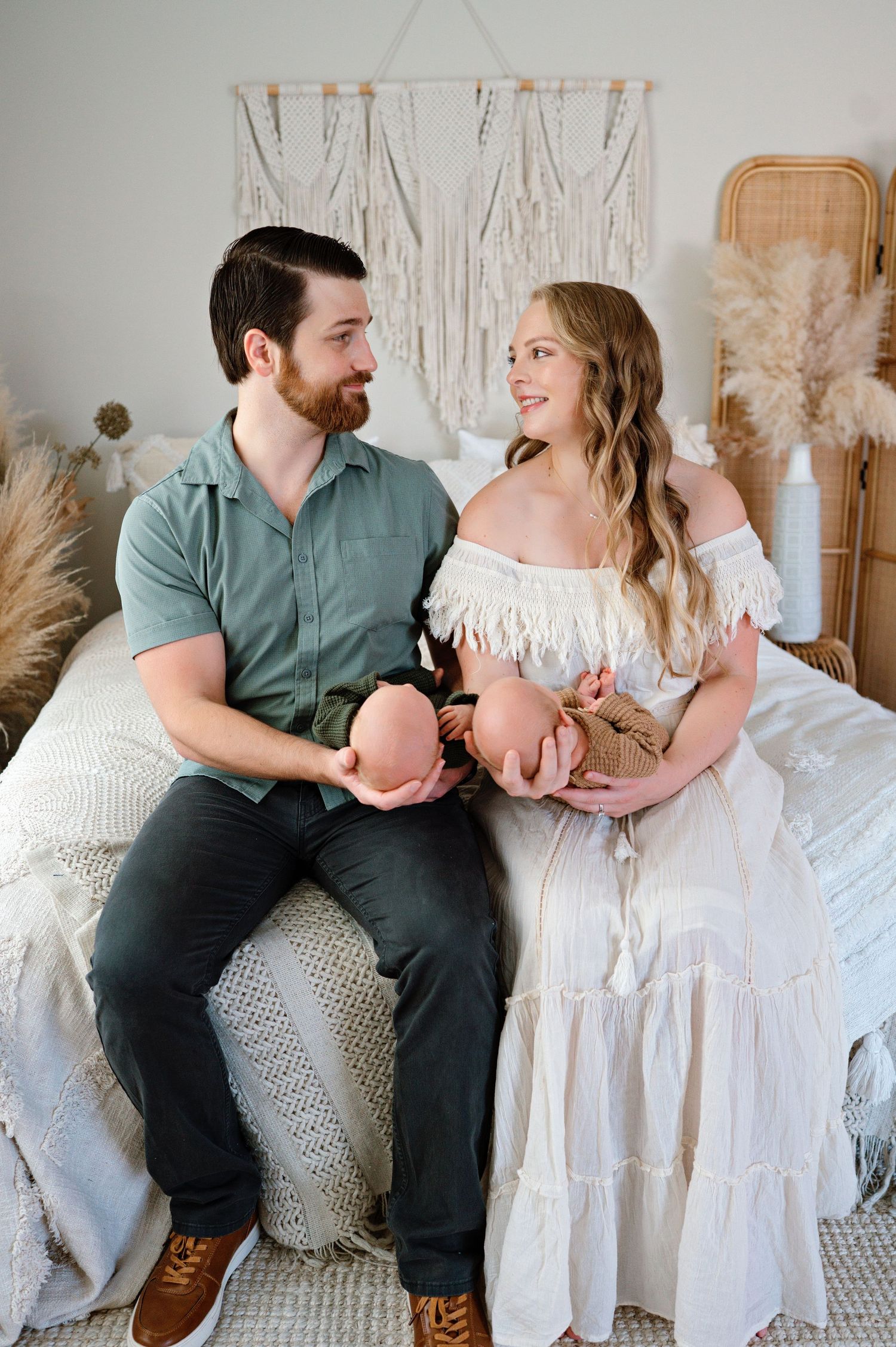 A couple in casual attire shares intimate moments while sitting together on a white couch in a bright room.