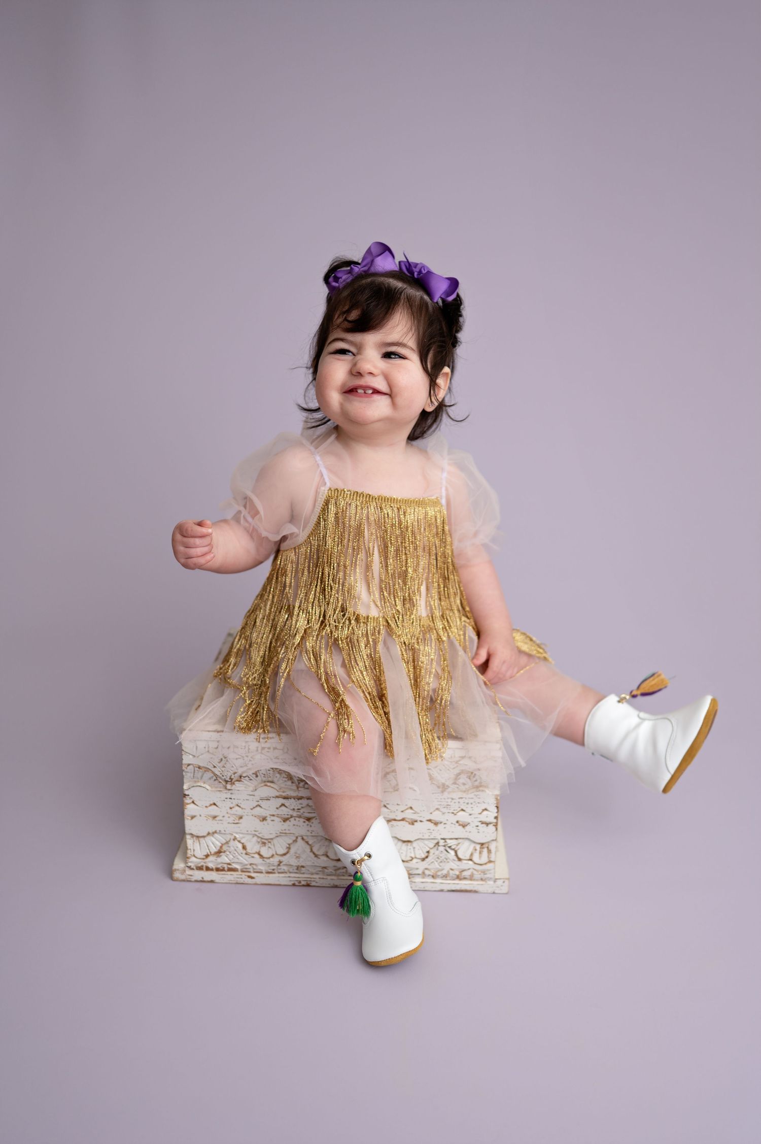 A series of photos showing a child in a gold fringe dress and purple flower hair accessory sitting on a lace cushion.