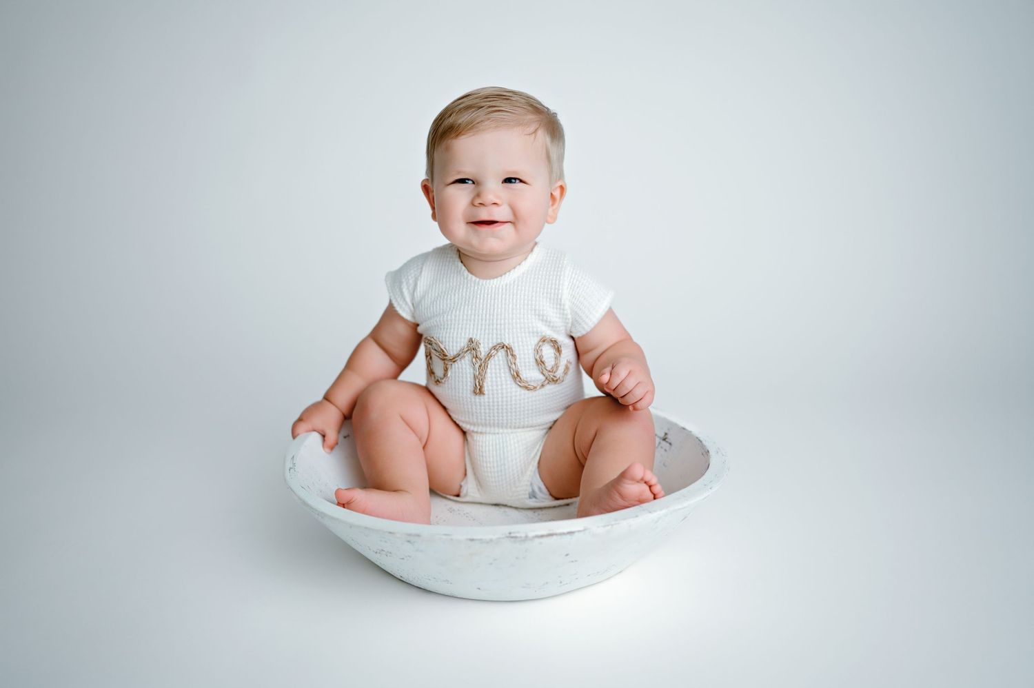 Baby's progressive growth sequence shown in a white bath seat against light gray background during their first year.