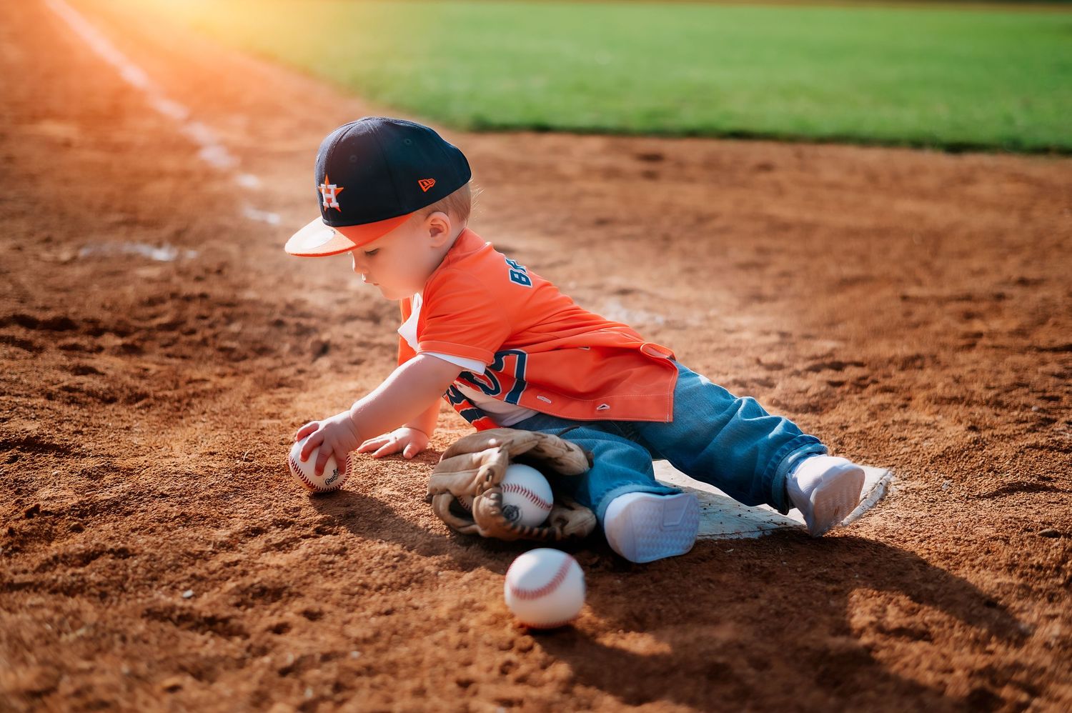 Baseball-themed photo session on dirt infield with sports equipment.