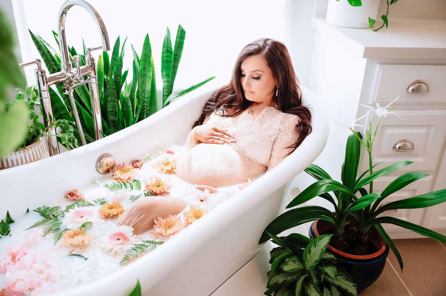 A relaxing white bathtub surrounded by lush green tropical plants creates a spa-like bathroom atmosphere.