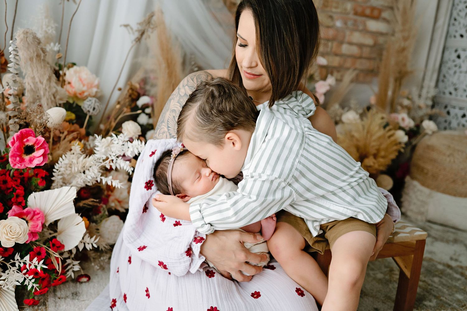 A family portrait showing tender affection with a newborn baby against a floral backdrop.