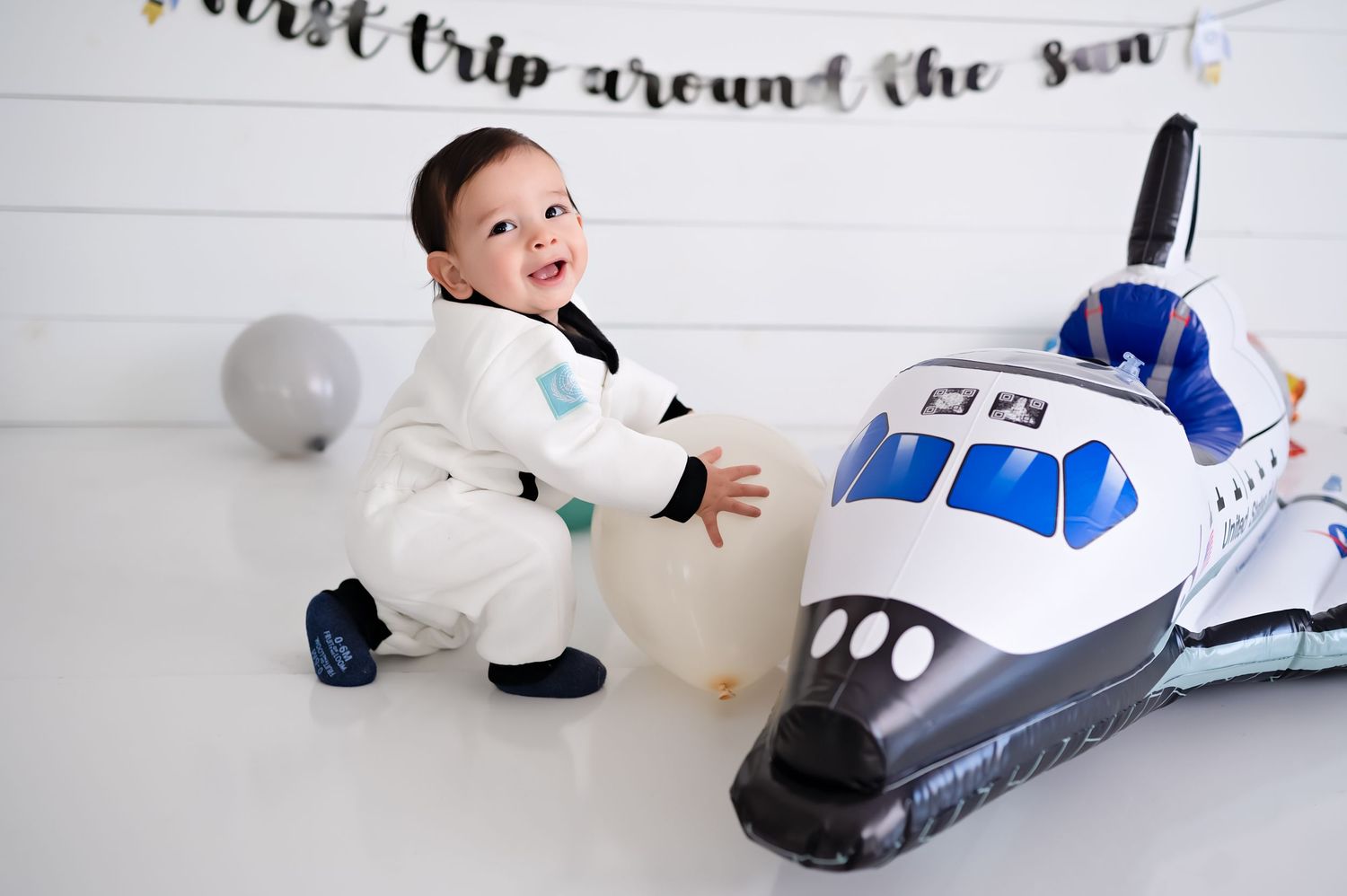 Four sequential photos showing someone interacting with a large plush toy airplane while laying on a white floor.