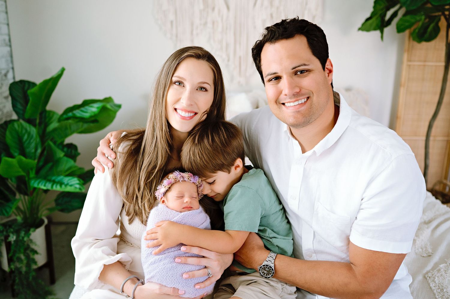 Bright family portrait with casual white and blue outfits against interior backdrop.