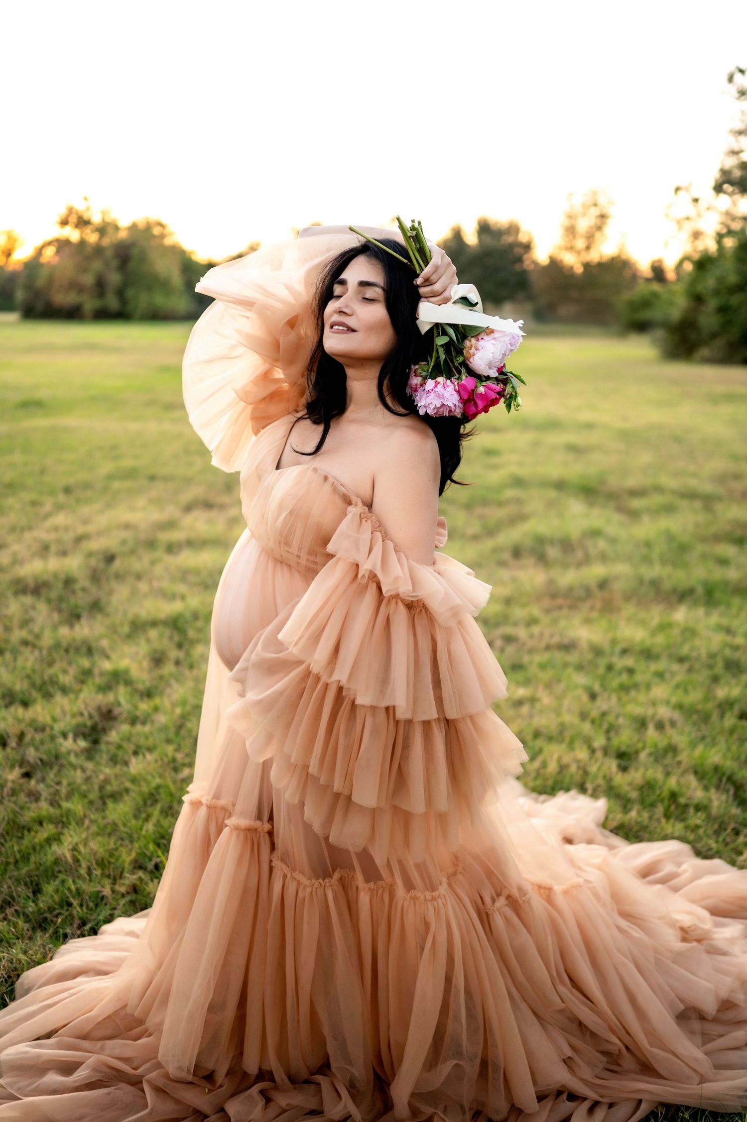 Ethereal peach tulle gown with cascading ruffles flows across a sunlit meadow during golden hour.