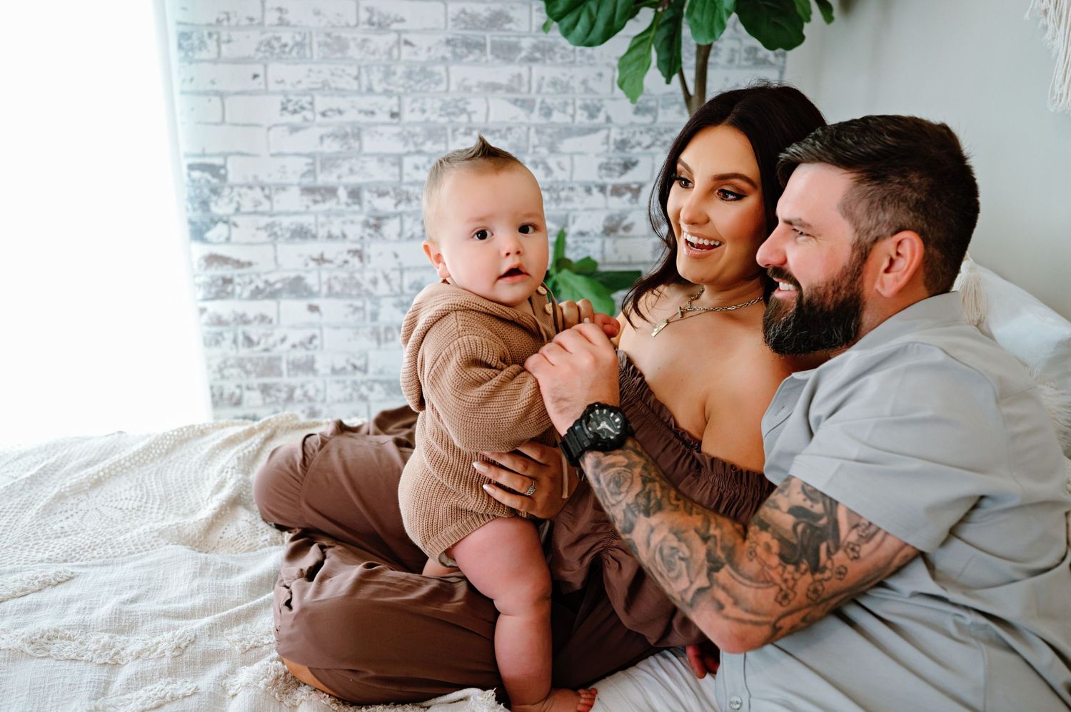 A family sits together on a white couch sharing tender moments in a modern living room setting.
