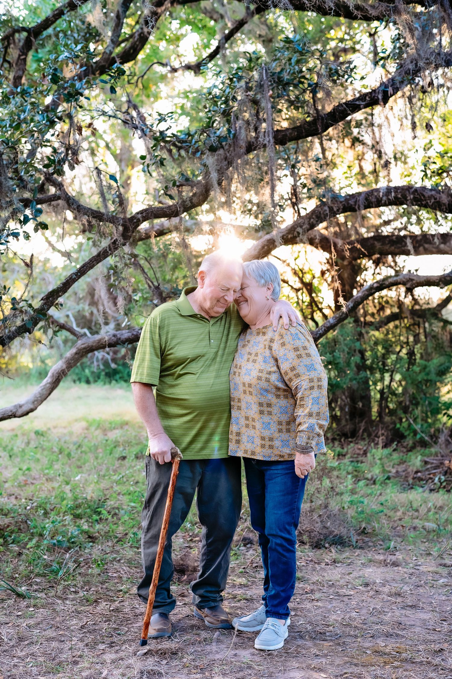 Elderly couple sharing tender moment while walking on nature trail.