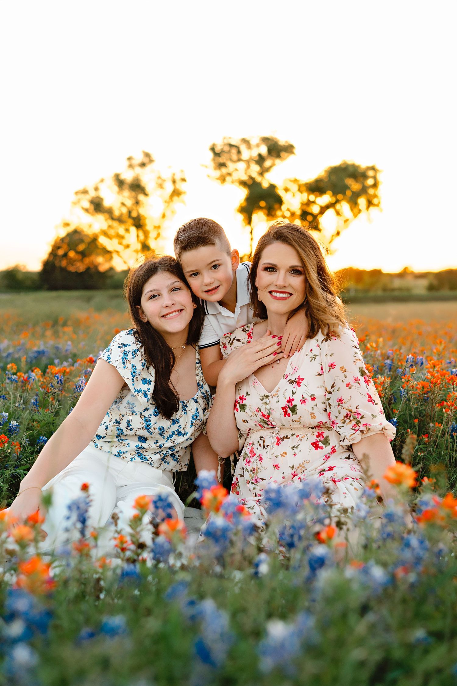 A springtime portrait in a wildflower field filled with bluebonnets and orange blooms at sunset.