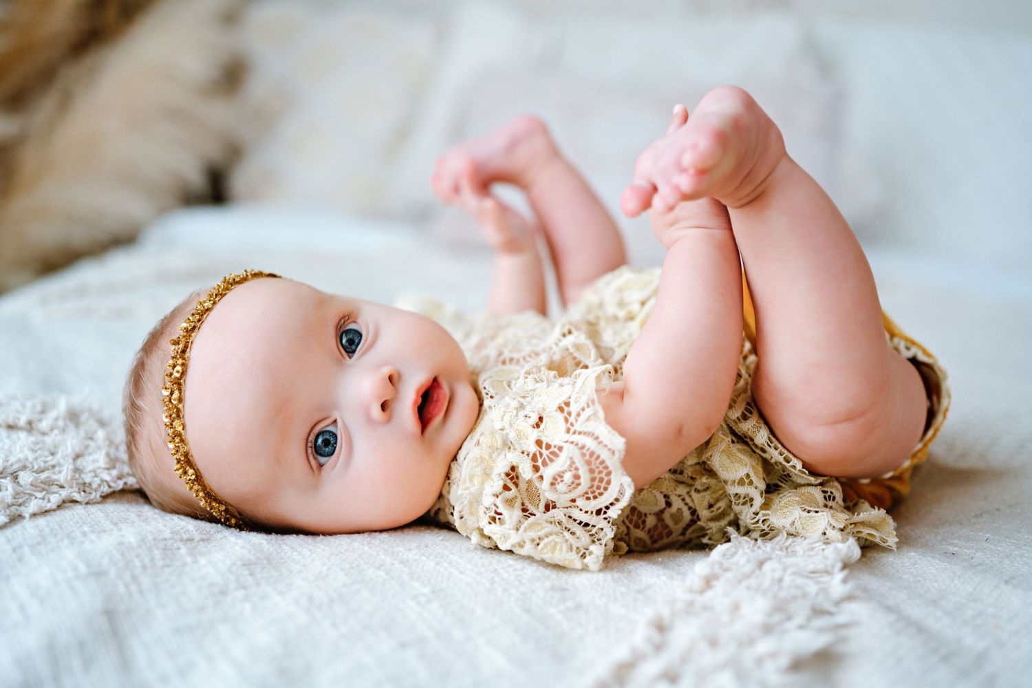 A sweet newborn photography session featuring a baby lying on soft white fabric with delicate lace details.