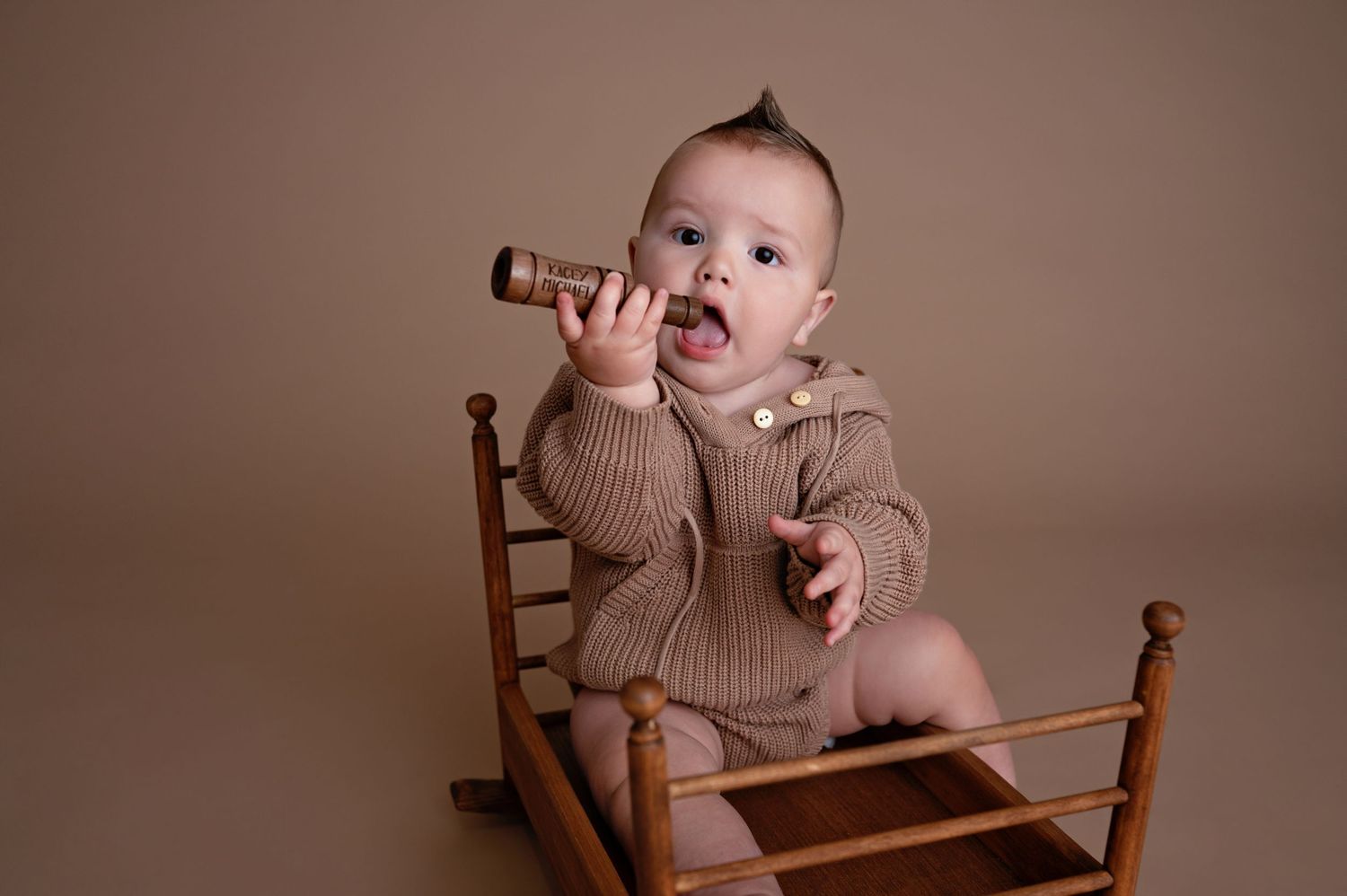 A wooden high chair stands against a warm brown background, evoking a nostalgic nursery feel.