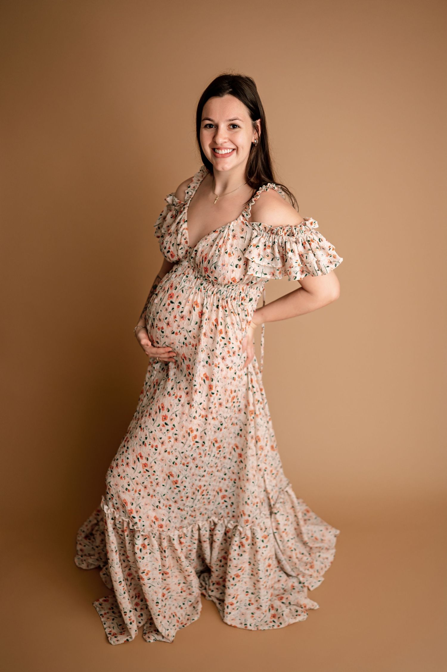 A floral maternity dress twirls gracefully against a warm brown backdrop in a series of flowing movement shots.