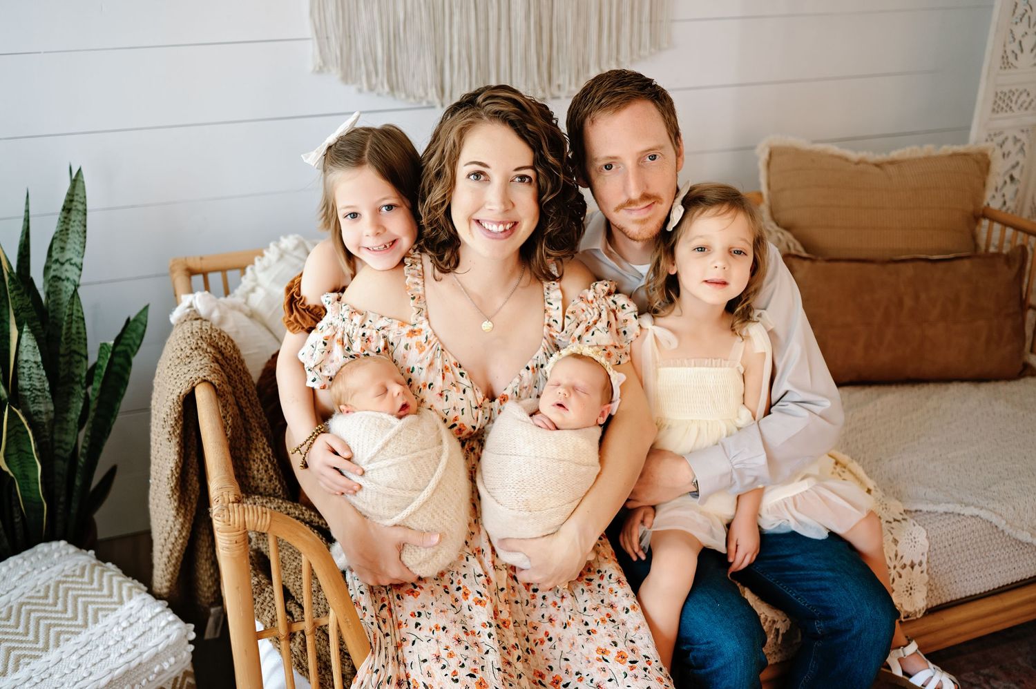 A group of people wearing coordinated neutral and cream colored outfits pose together in a bright interior setting.