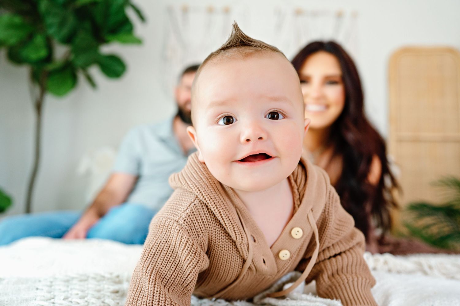 Little one lying on soft bedding wearing a cozy beige sweater during an indoor lifestyle photography session.
