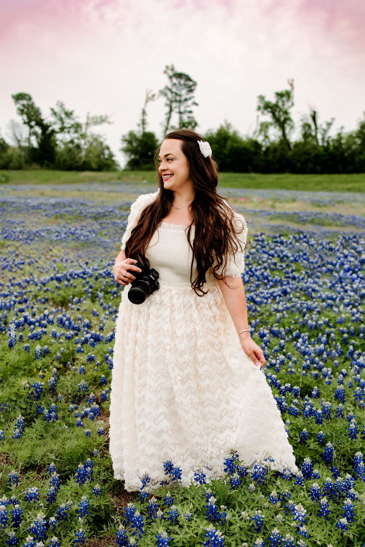 White lace dress photographed in field of blooming bluebonnets on sunny day.