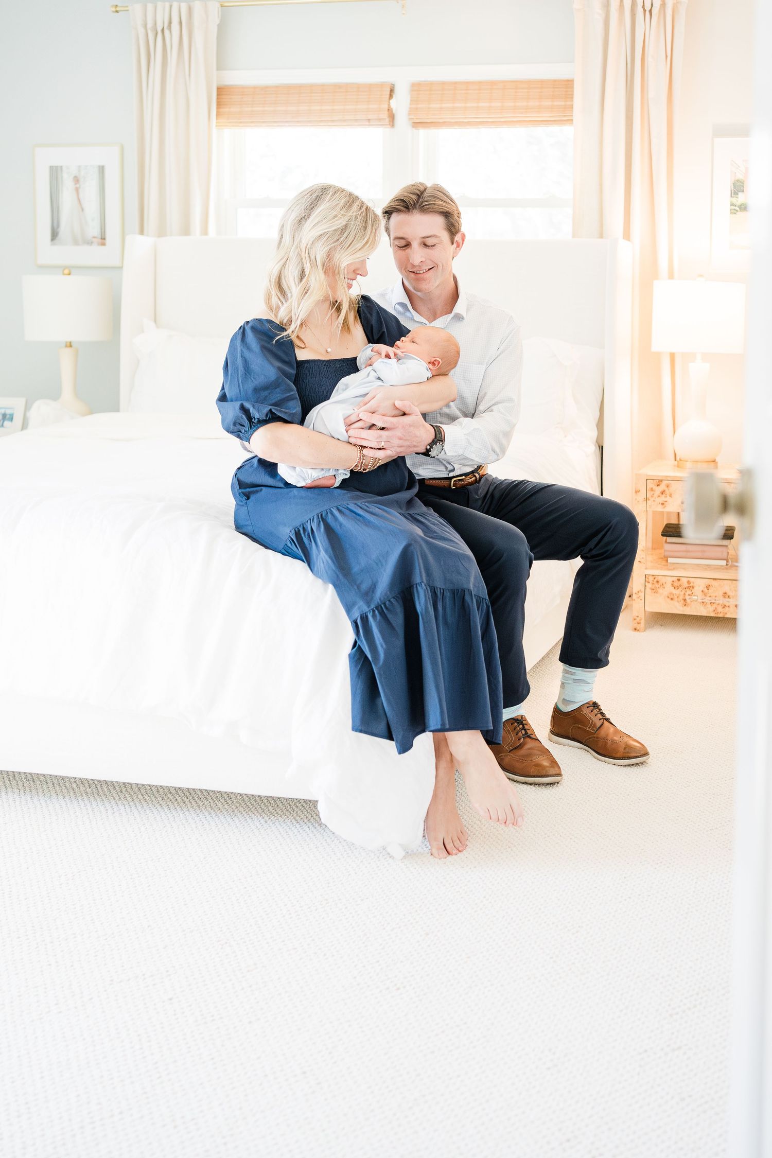 New parents Laney and Chandler holding newborn son in their living room with natural light