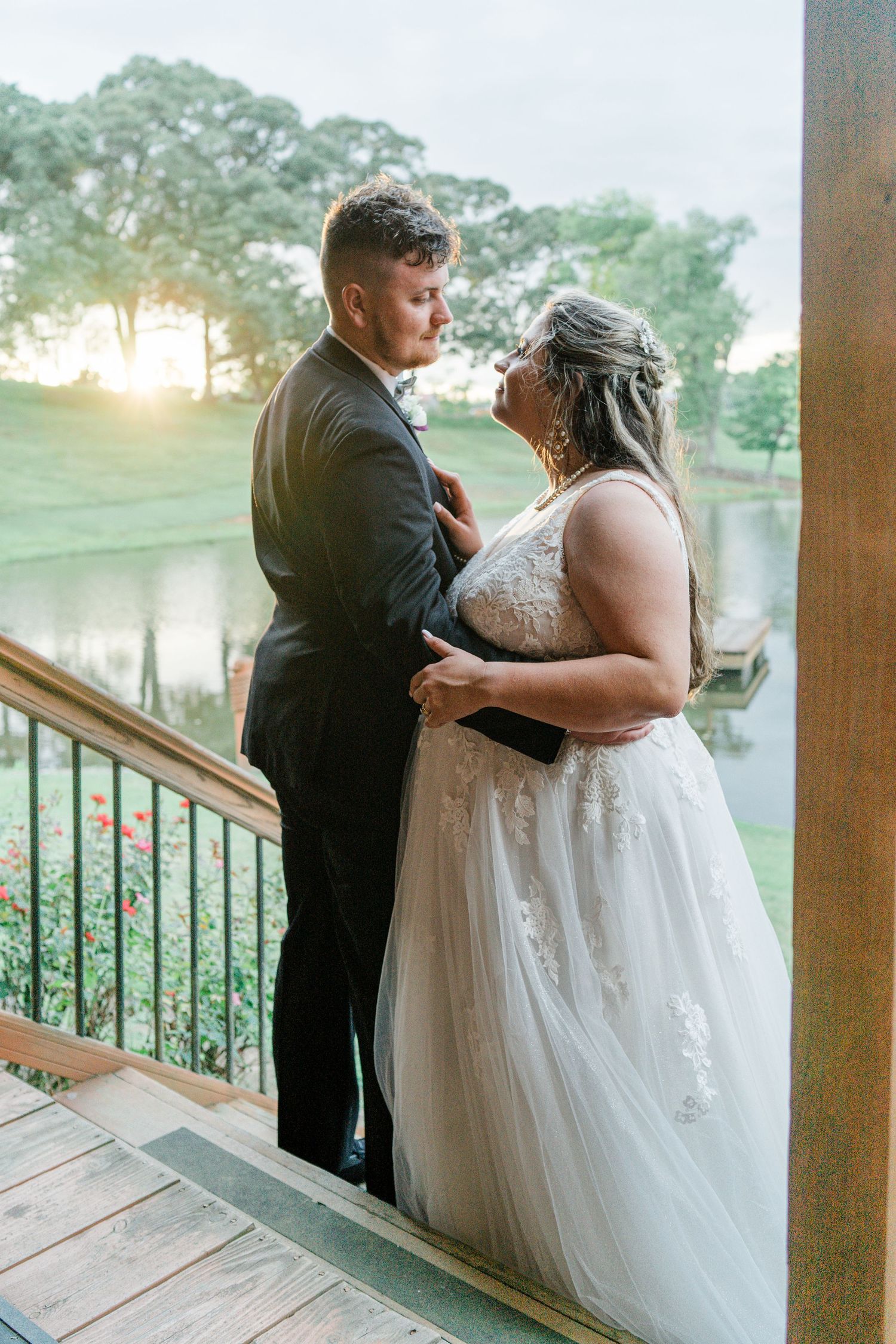 bride and groom facing each other on cabin stairs with the pond and the golden hour sun in the background