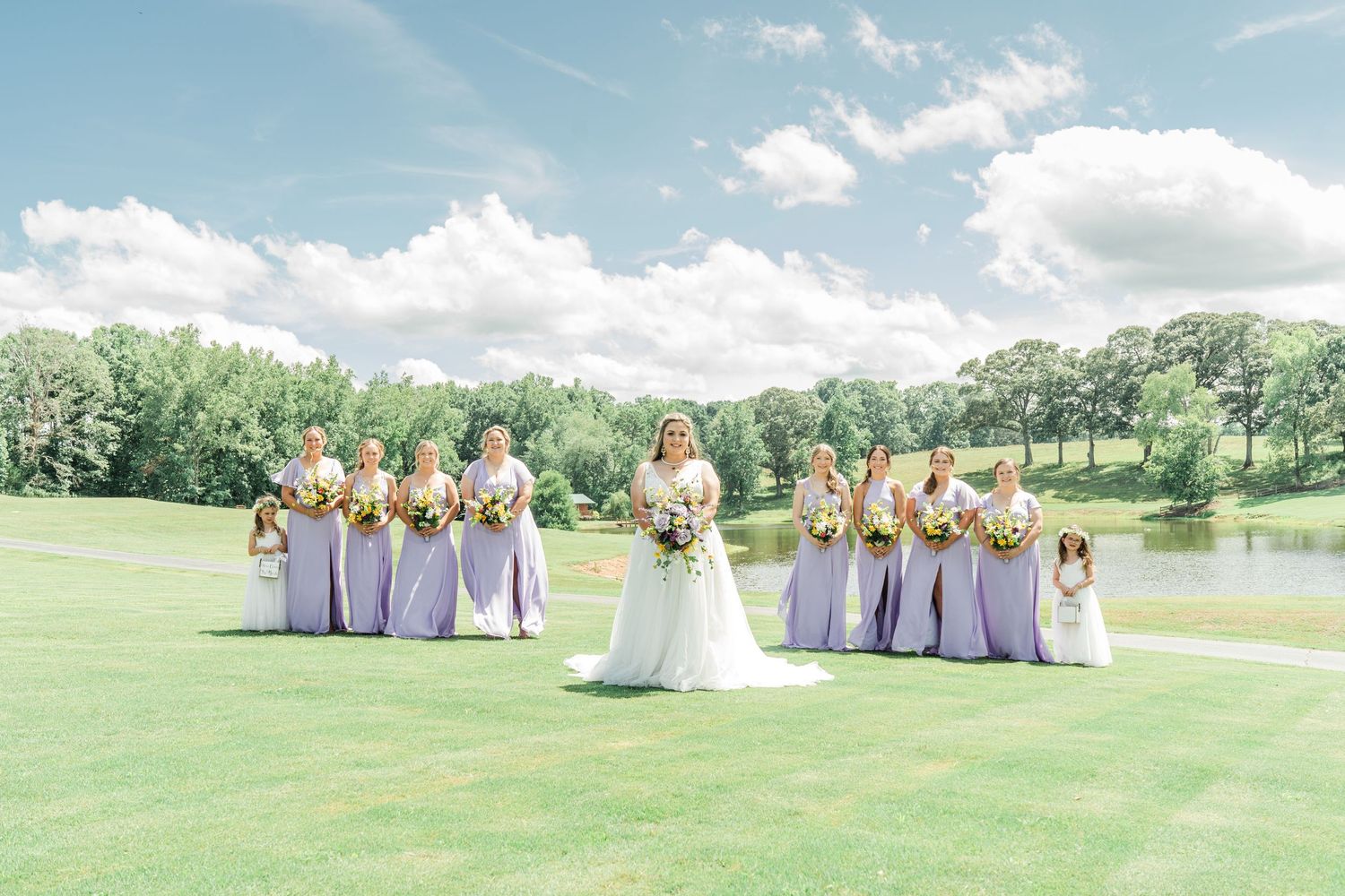 bride and bridesmaids outside in front of a pond