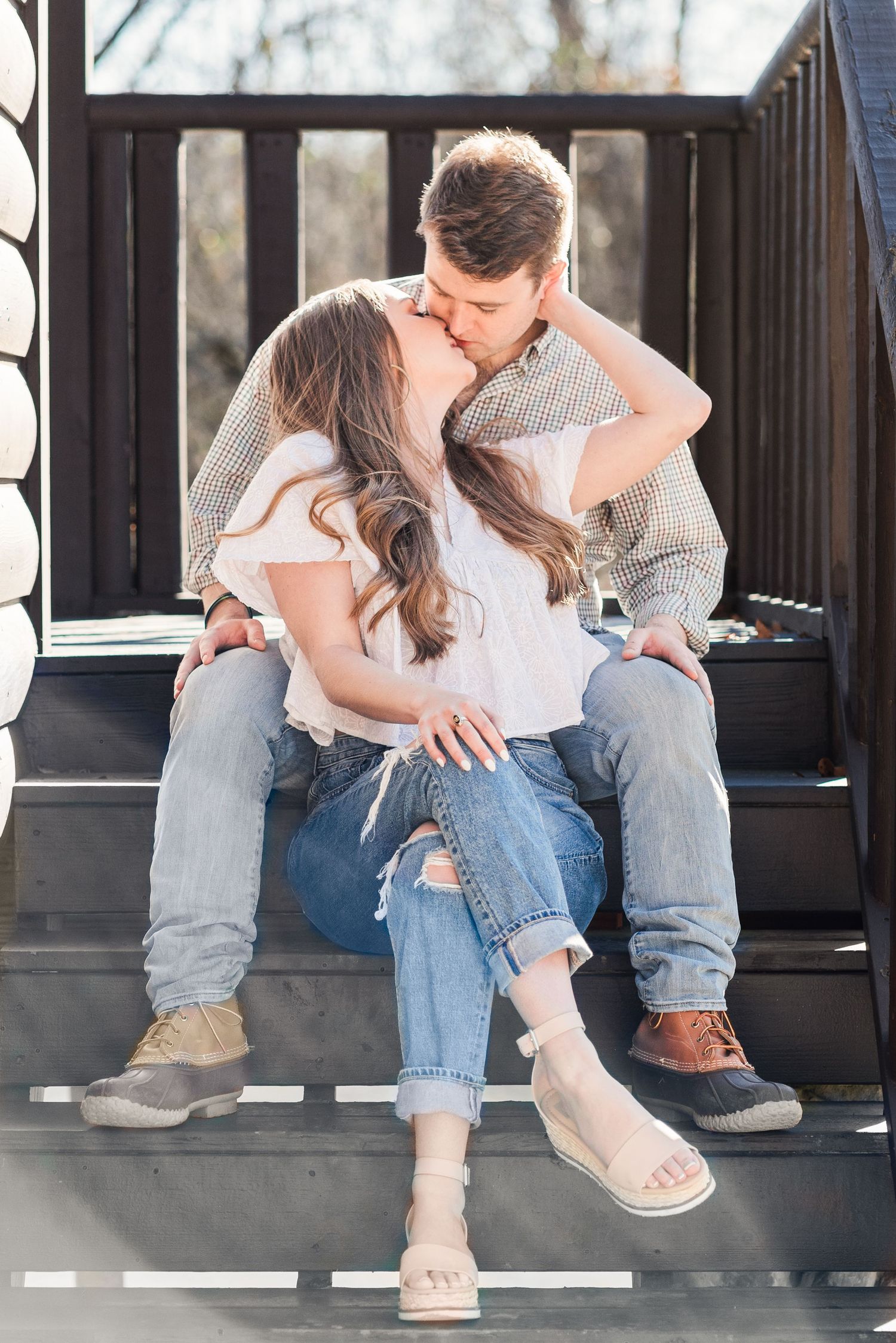 Clemson alumni couple sitting on the steps of a cabin sharing a romantic kiss