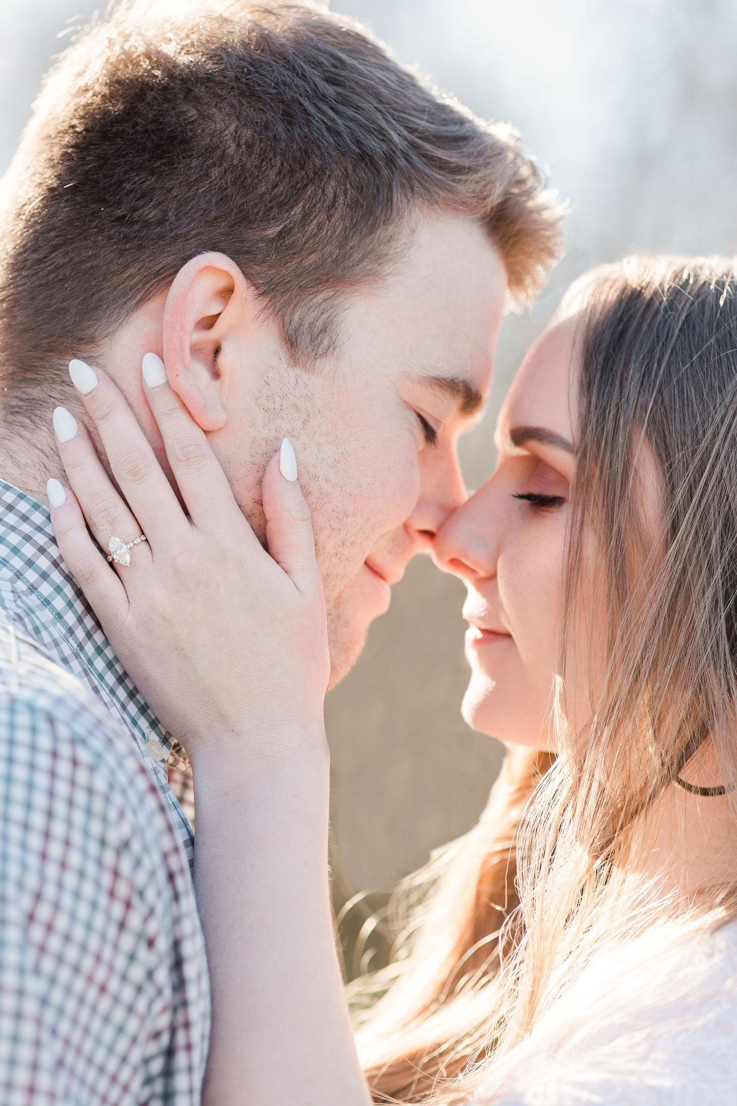 Engaged couple nose to nose with eyes closed in romantic photo