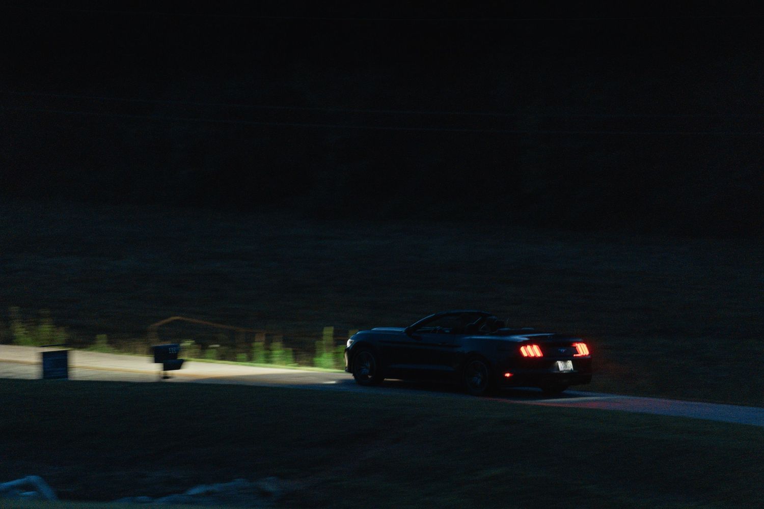 bride and groom driving away in a convertible