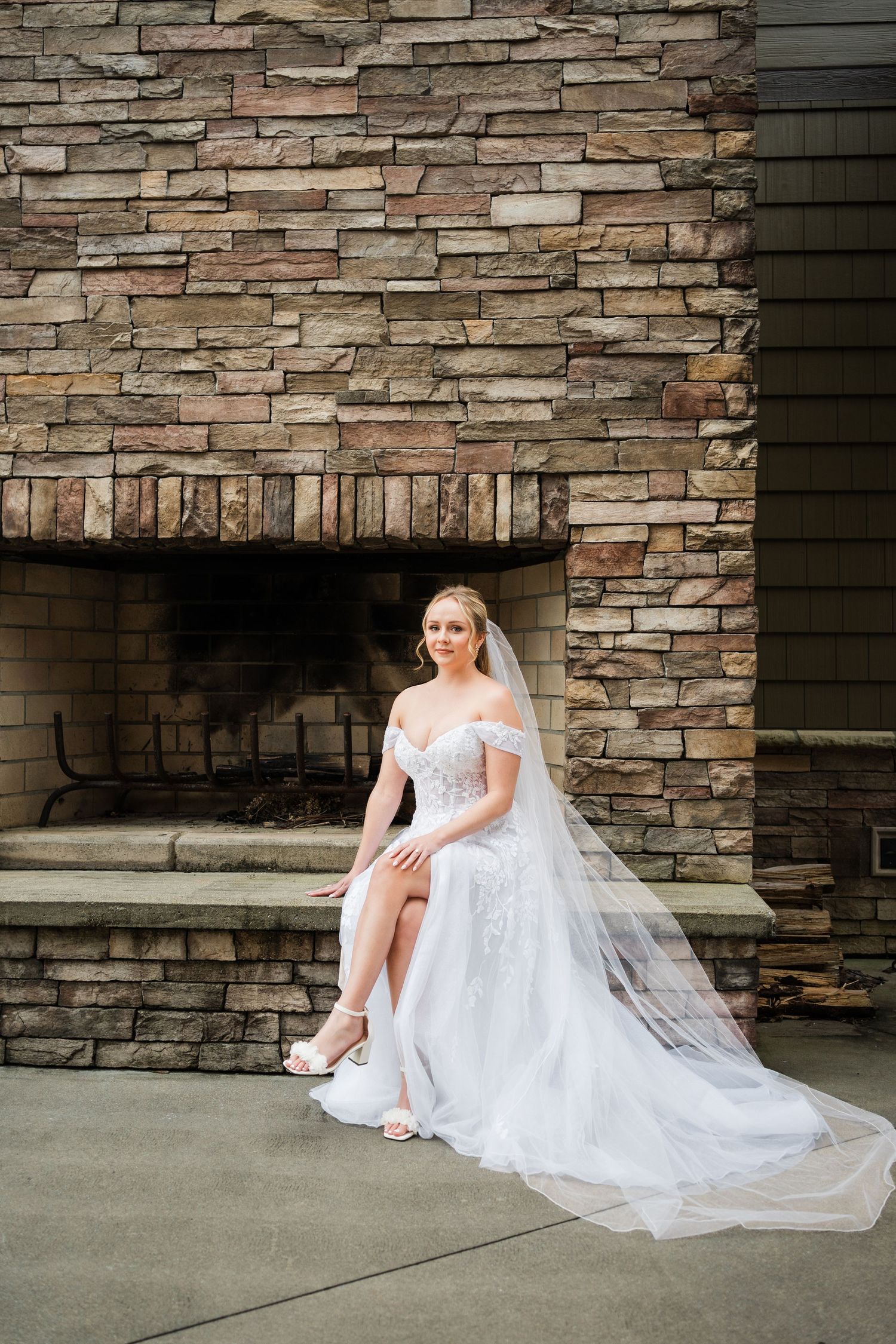 bride sitting with legs crossed on an outdoor fireplace hearth