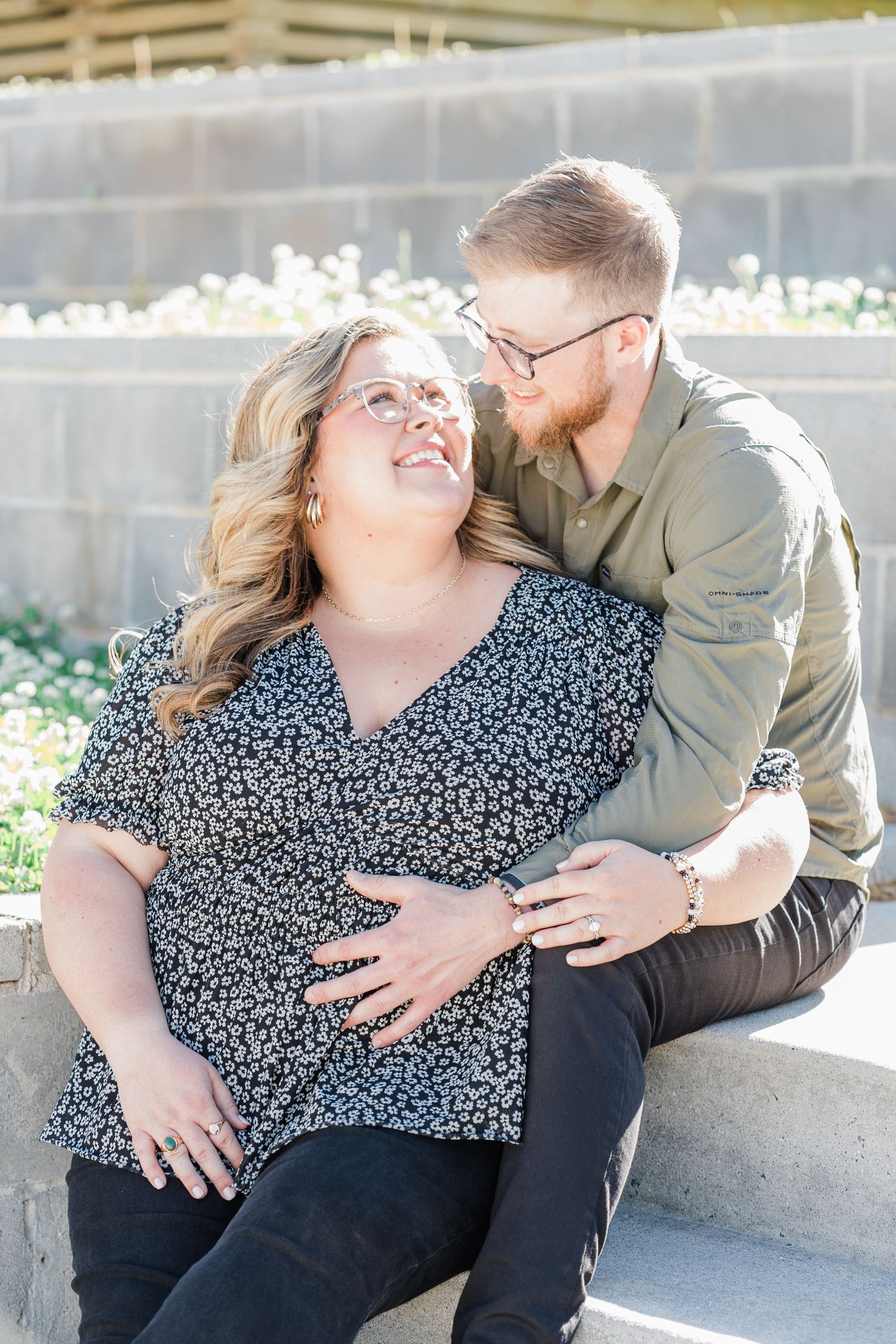 Man hugging woman from behind with her staring back up at him with a smile on her face.