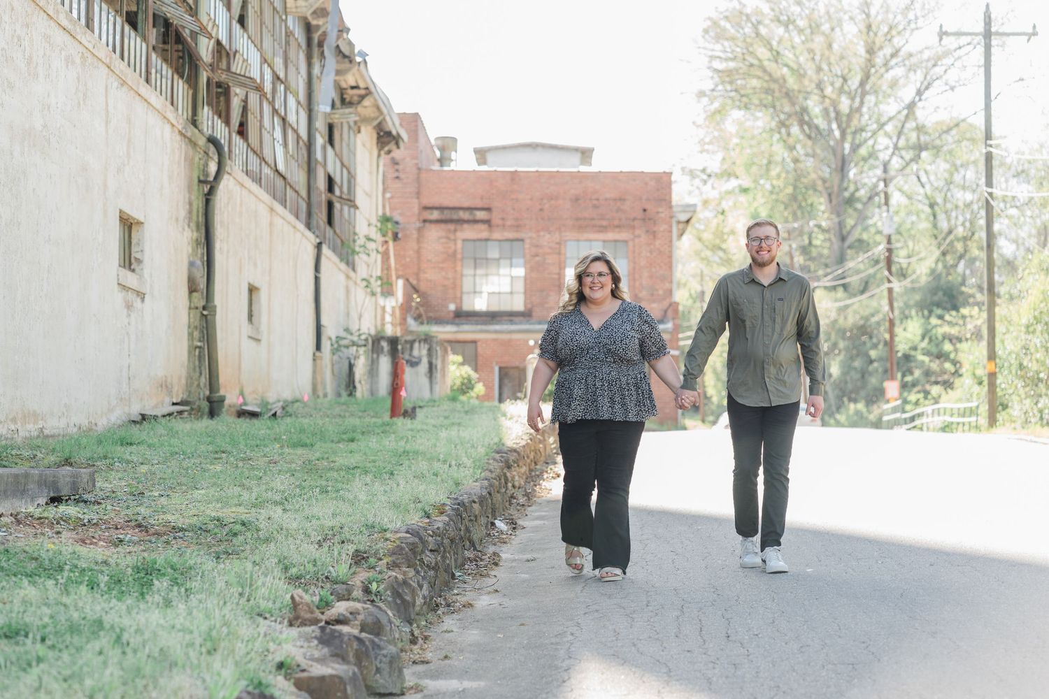 Man and woman holding hands and walking down the street in front of Taylors Mill headed toward Southern Bleachery